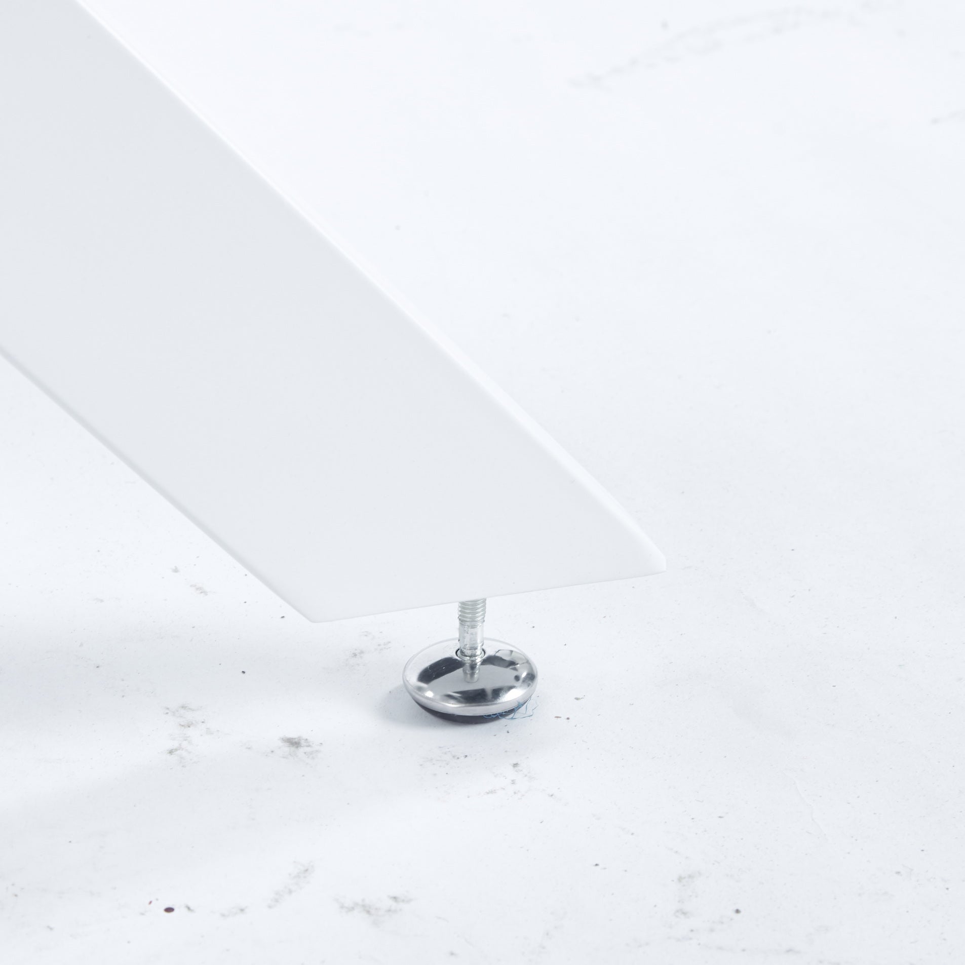 Closeup of a white table leg with adjustable leveling foot and chrome screw detail