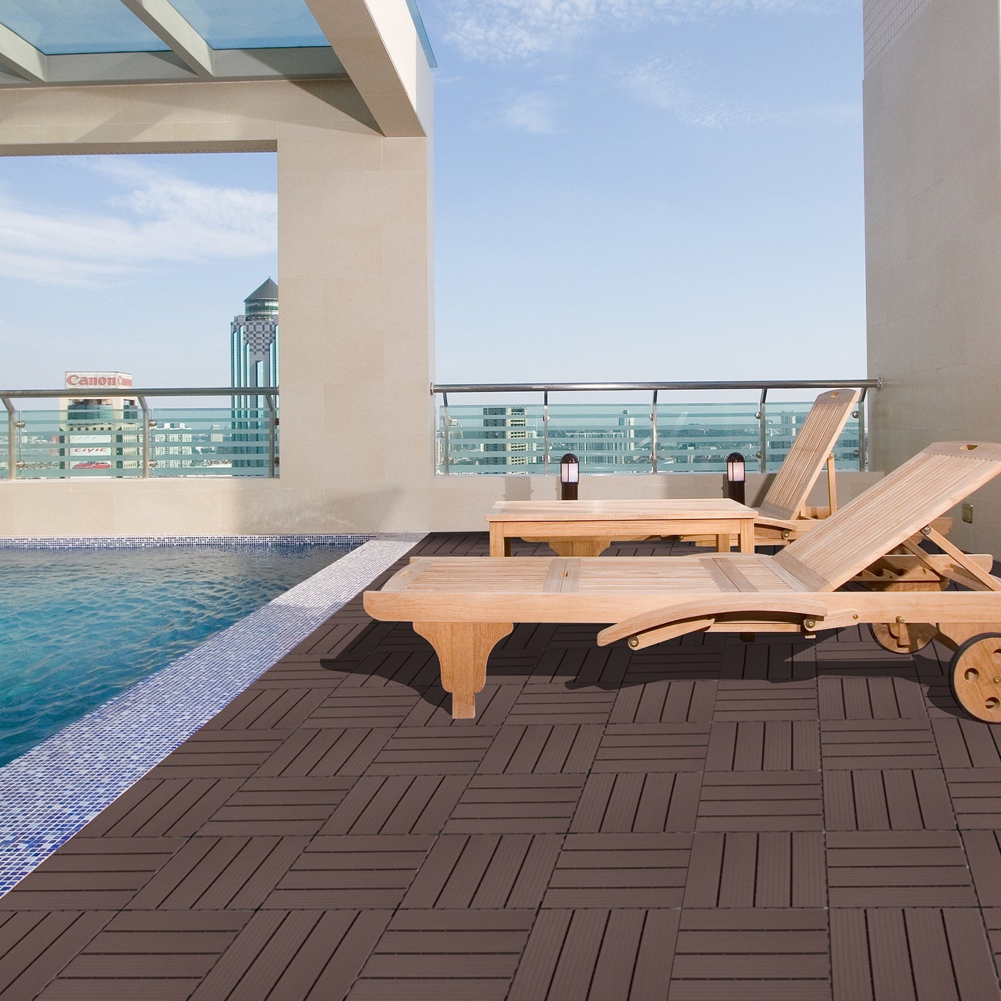 Rich brown composite deck tiles provide a modern base for this poolside lounge area with wooden furniture