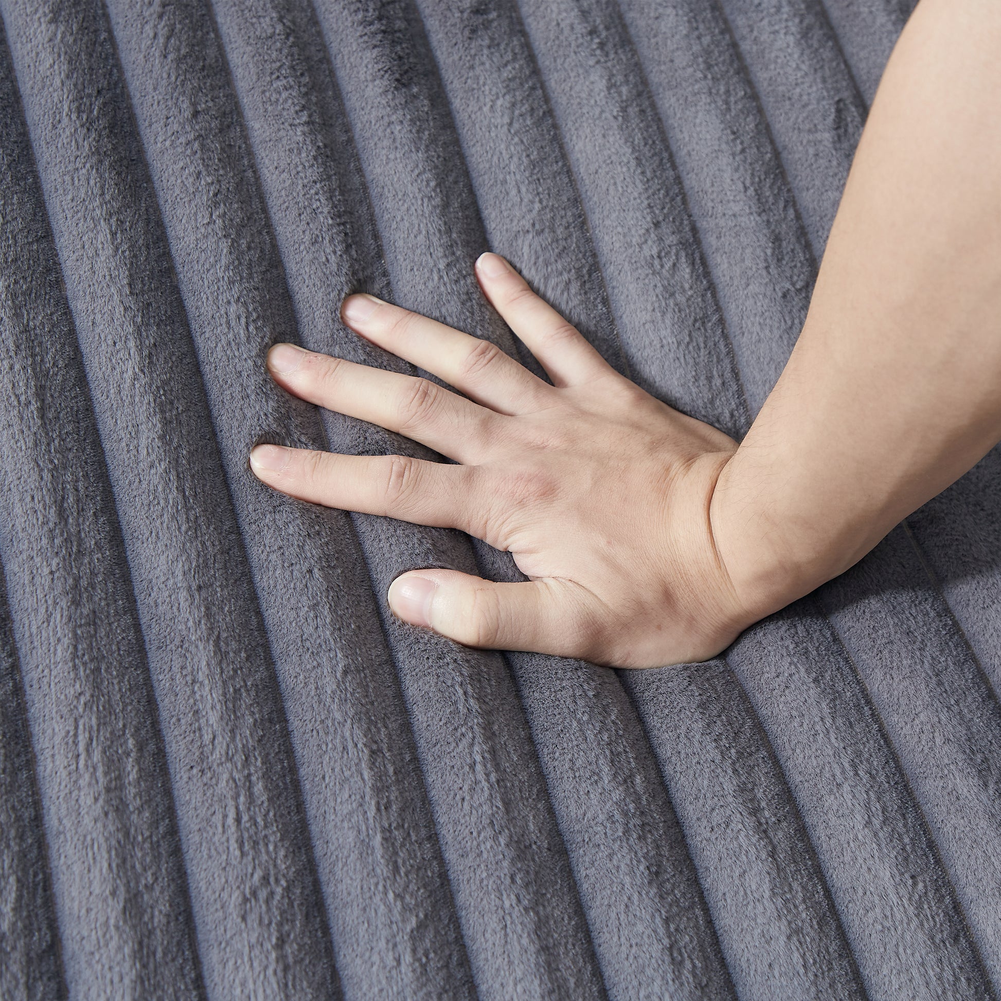 Hand pressing into plush grey ribbed velvet fabric showcasing softness