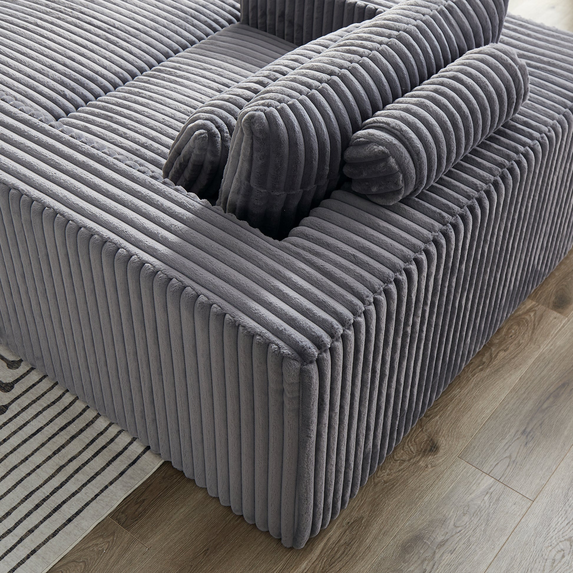 Plush grey corduroy sofa featuring deep channel tufting and soft bolster pillows for a cozy seating experience