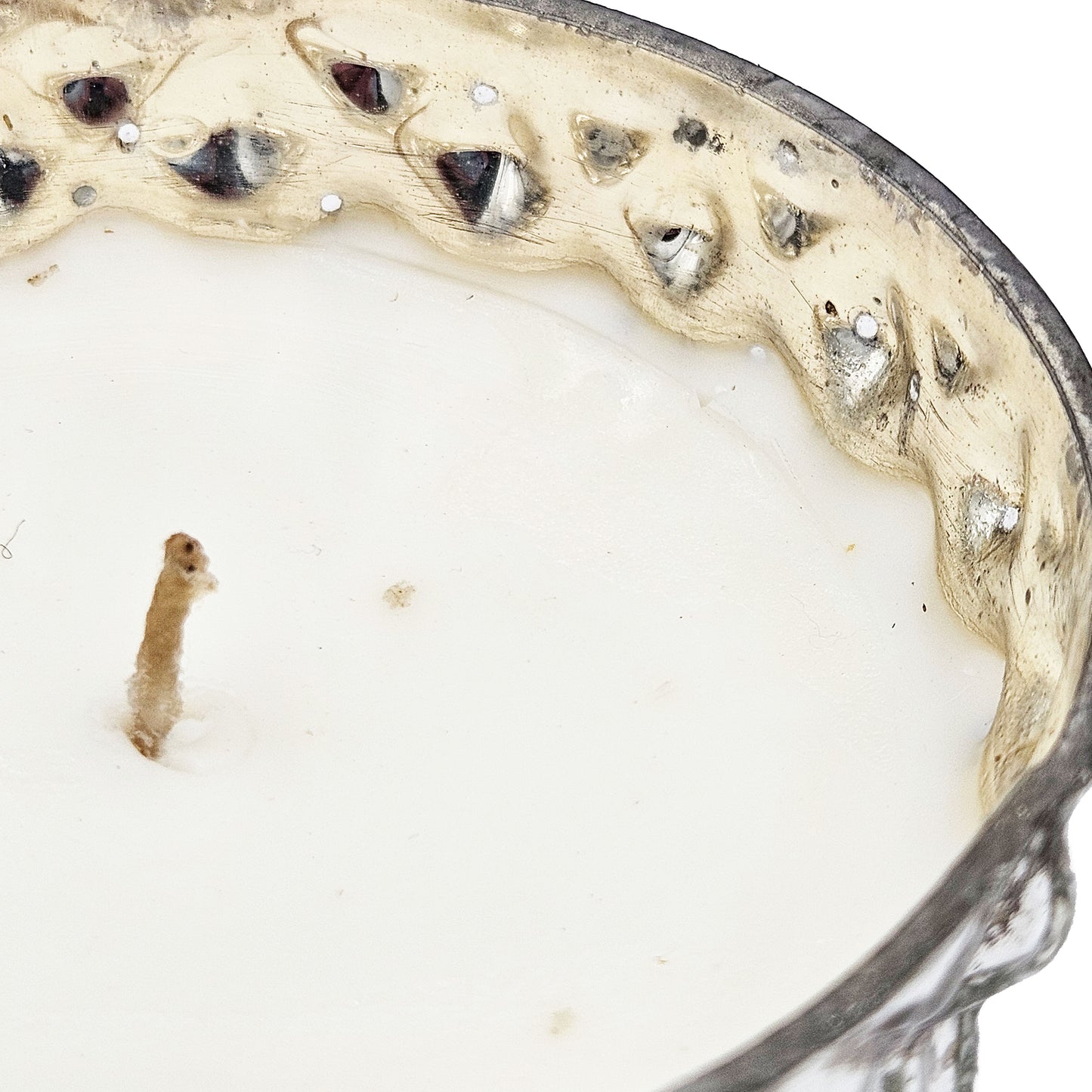 Closeup of an antique silver filigree decorative candle with a creamy white wax filler