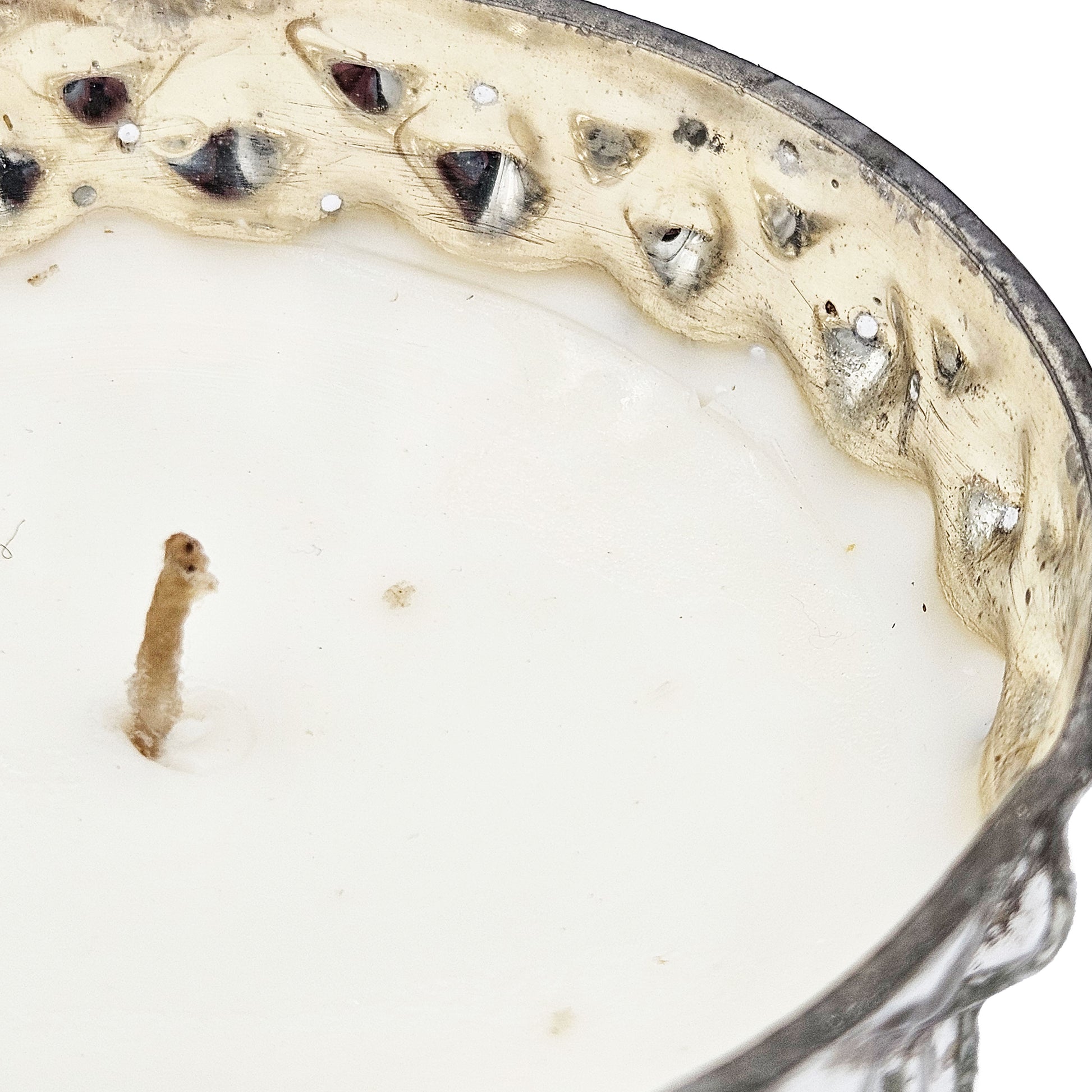 Closeup of an antique silver filigree decorative candle with a creamy white wax filler