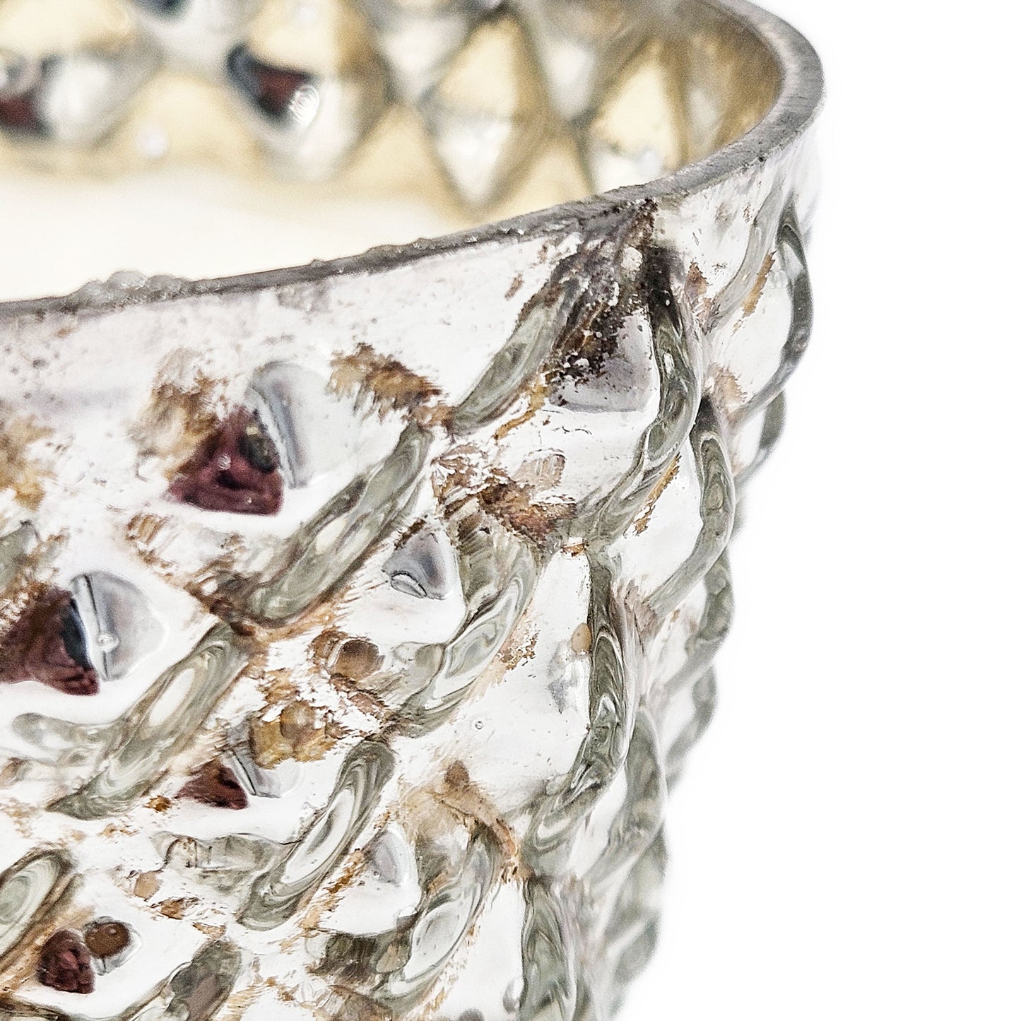 Closeup of a textured antique silver glass votive holder with diamond pattern reflecting light