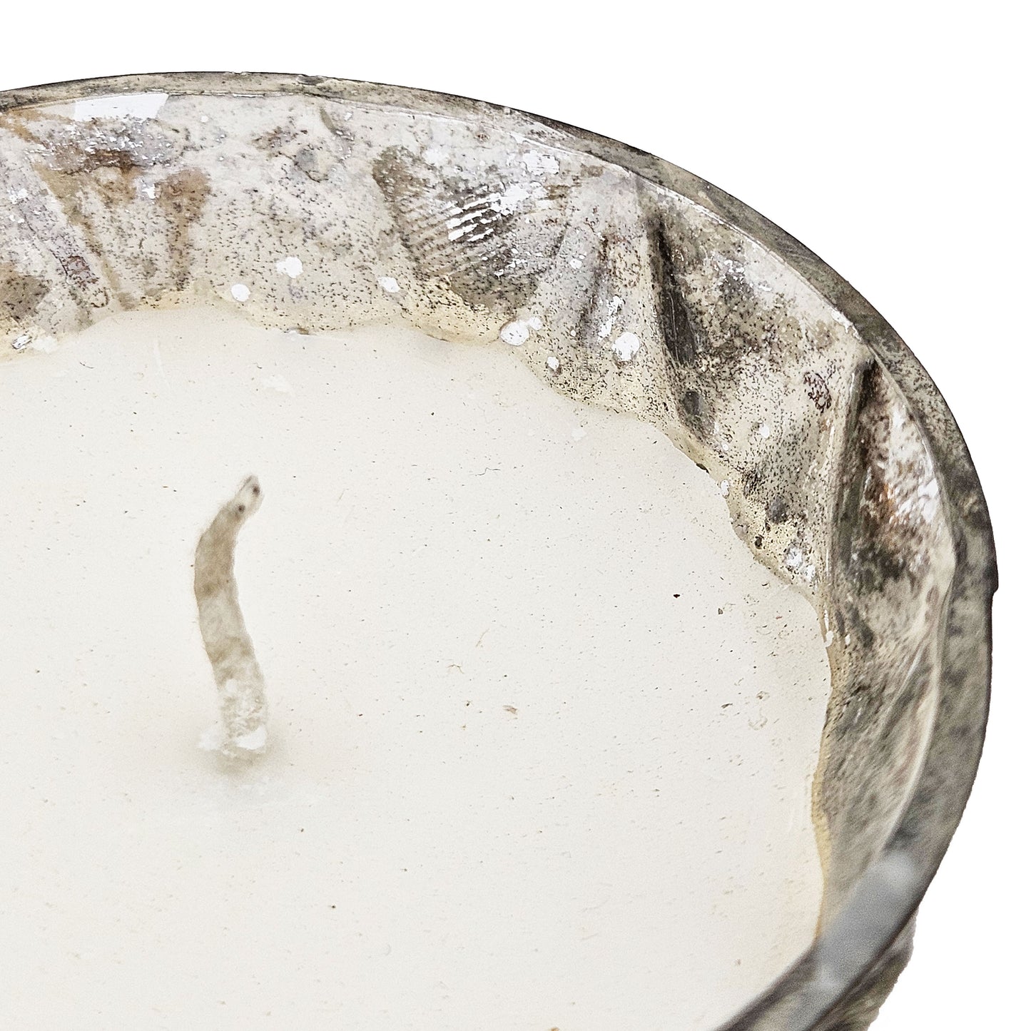 Closeup of a white soy wax candle in a textured distressed silver glass container for cozy home decor