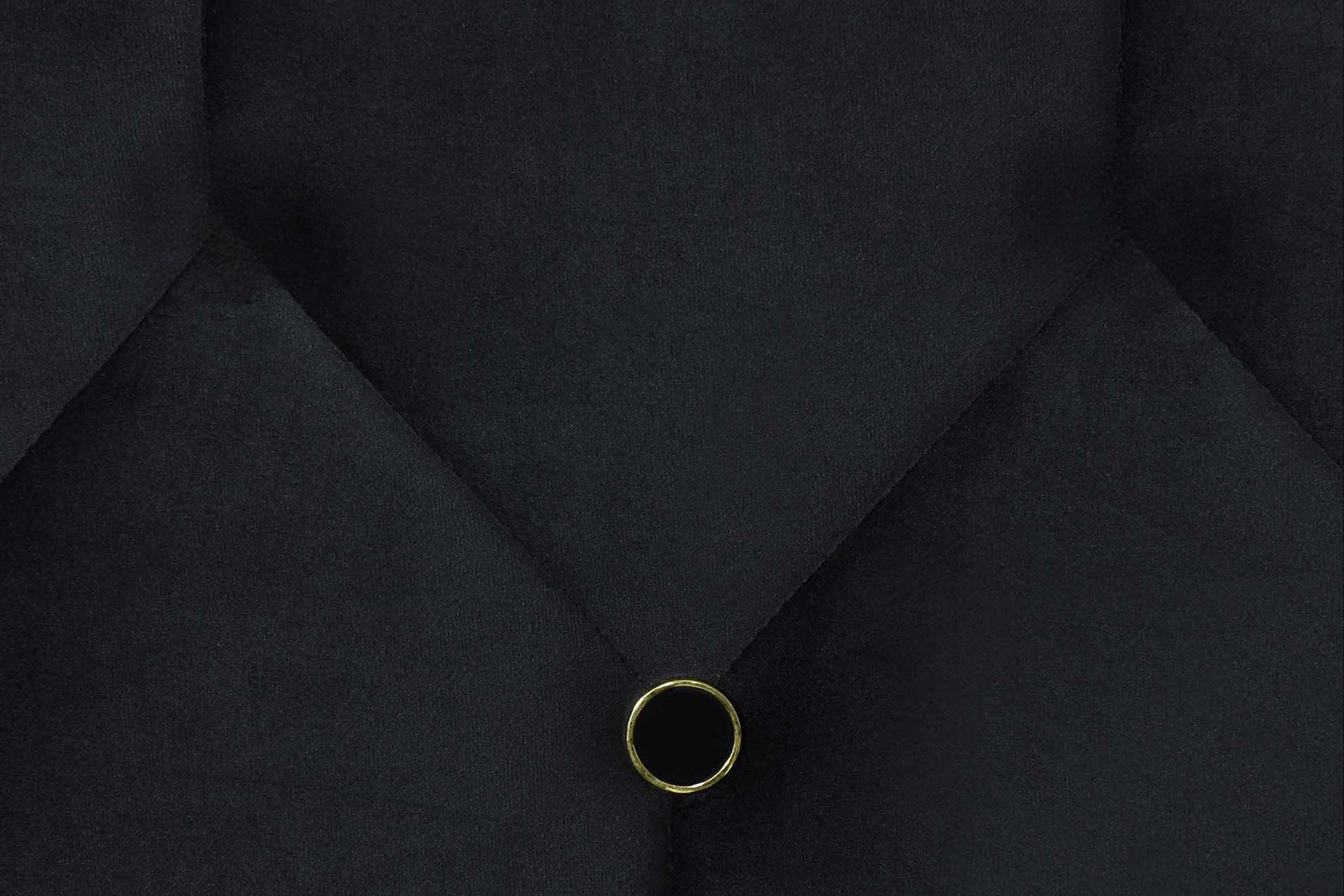 Black velvet tufted headboard detail with gold button accent