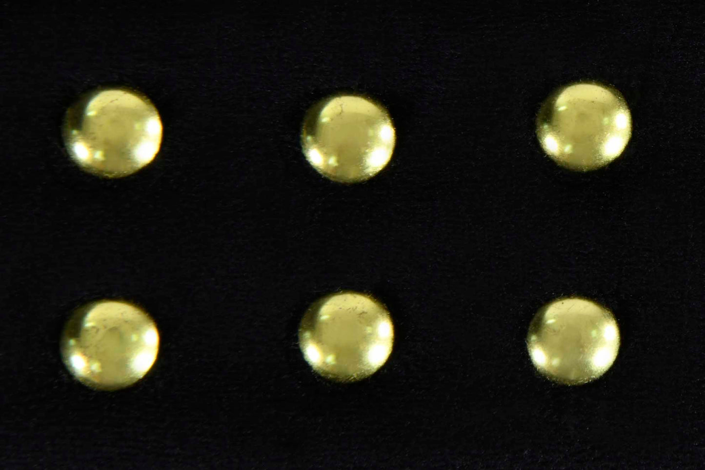 Six decorative brass studs on a black leather texture