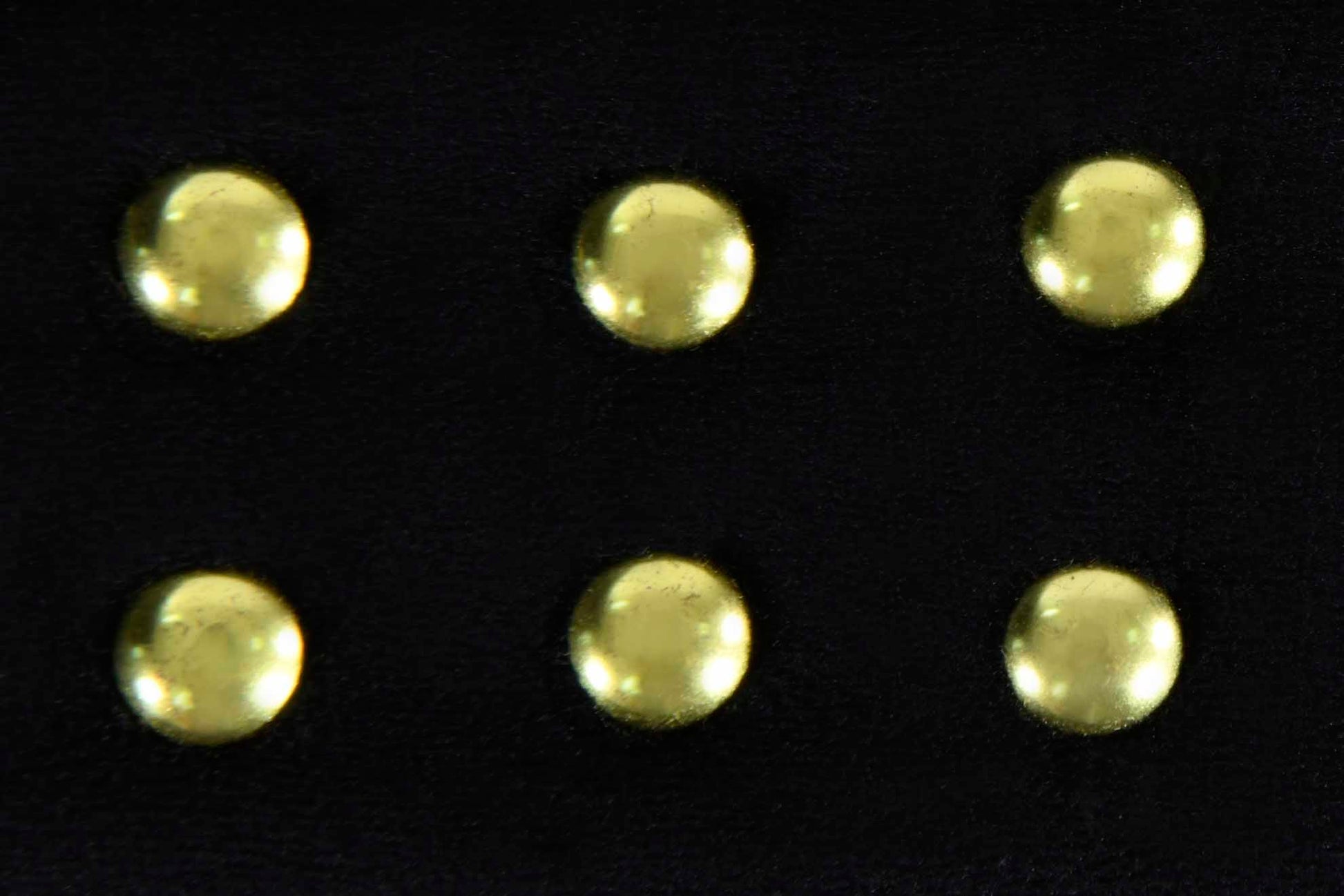 Six decorative brass studs on a black leather texture