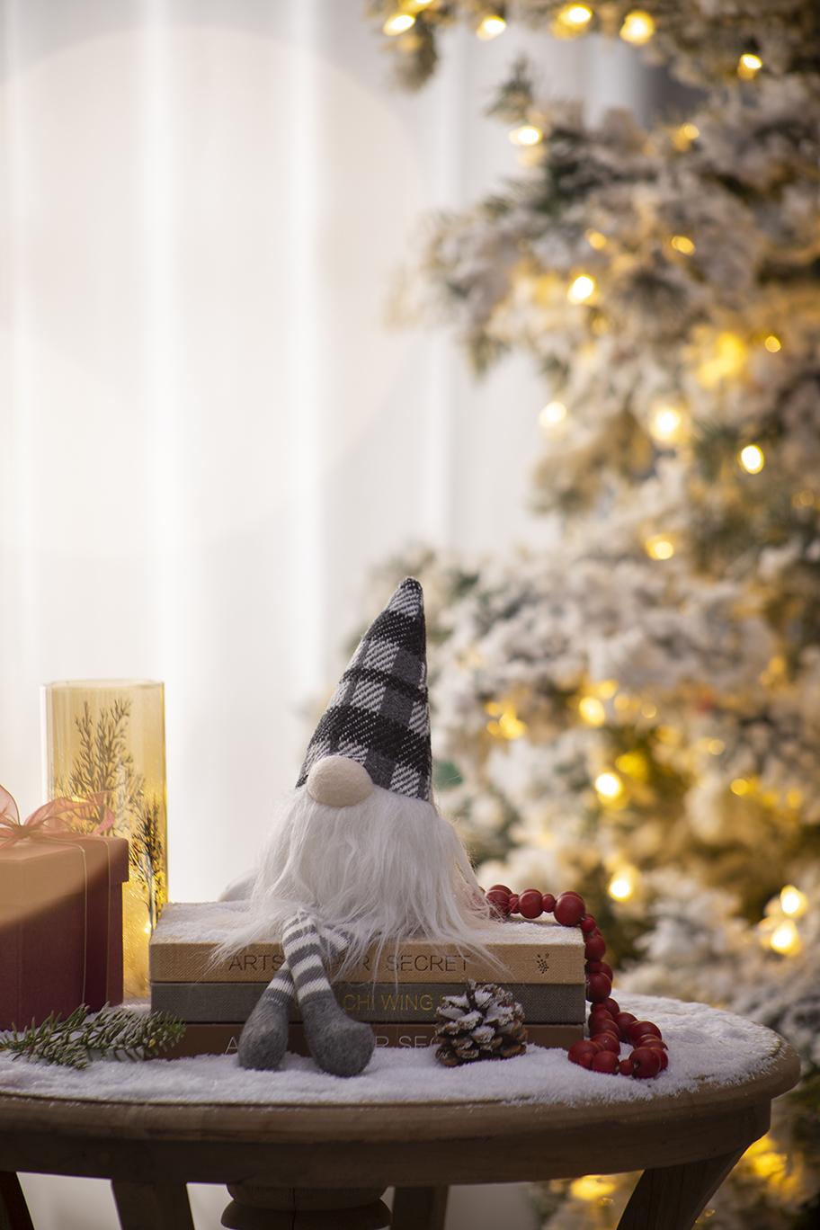 Plush Christmas gnome with gray plaid hat and white beard on stacked books