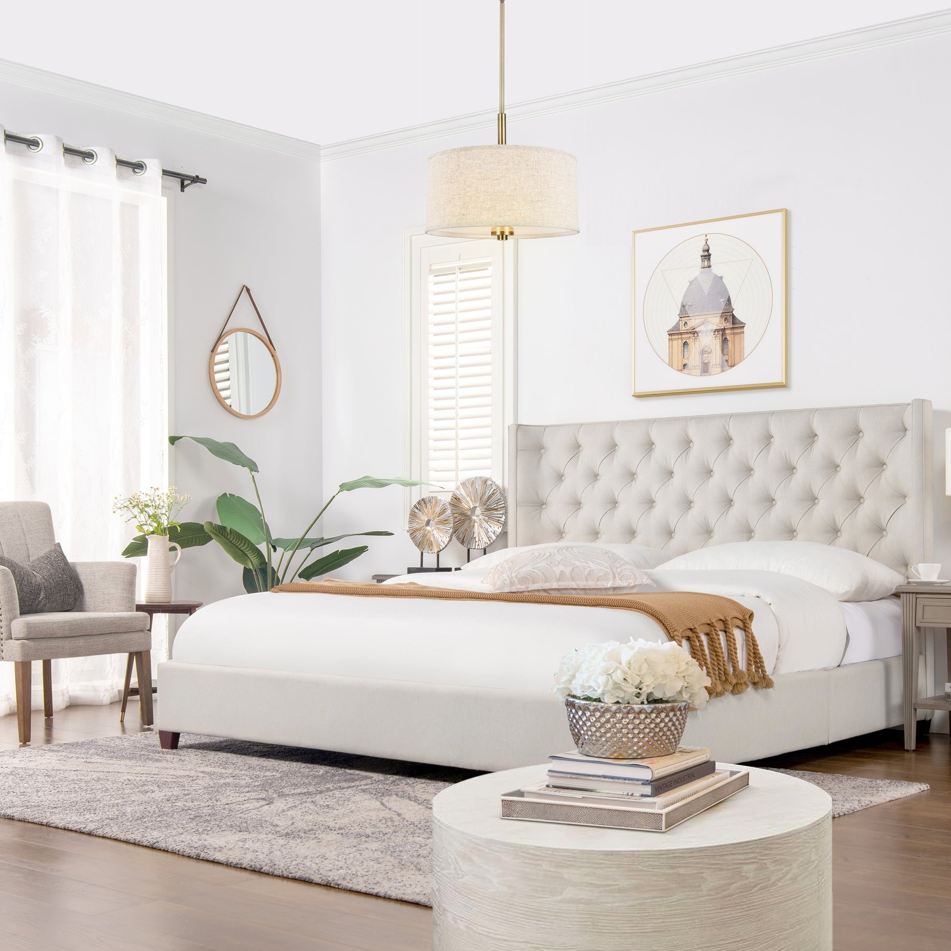 Upholstered beige bed frame with button tufting and crisp white linens a warm accent throw
