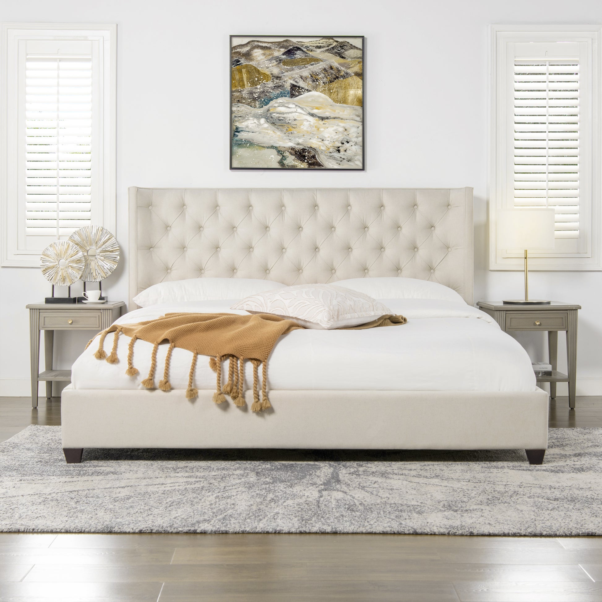 Cream upholstered platform bed with tufted headboard and camel throw blanket