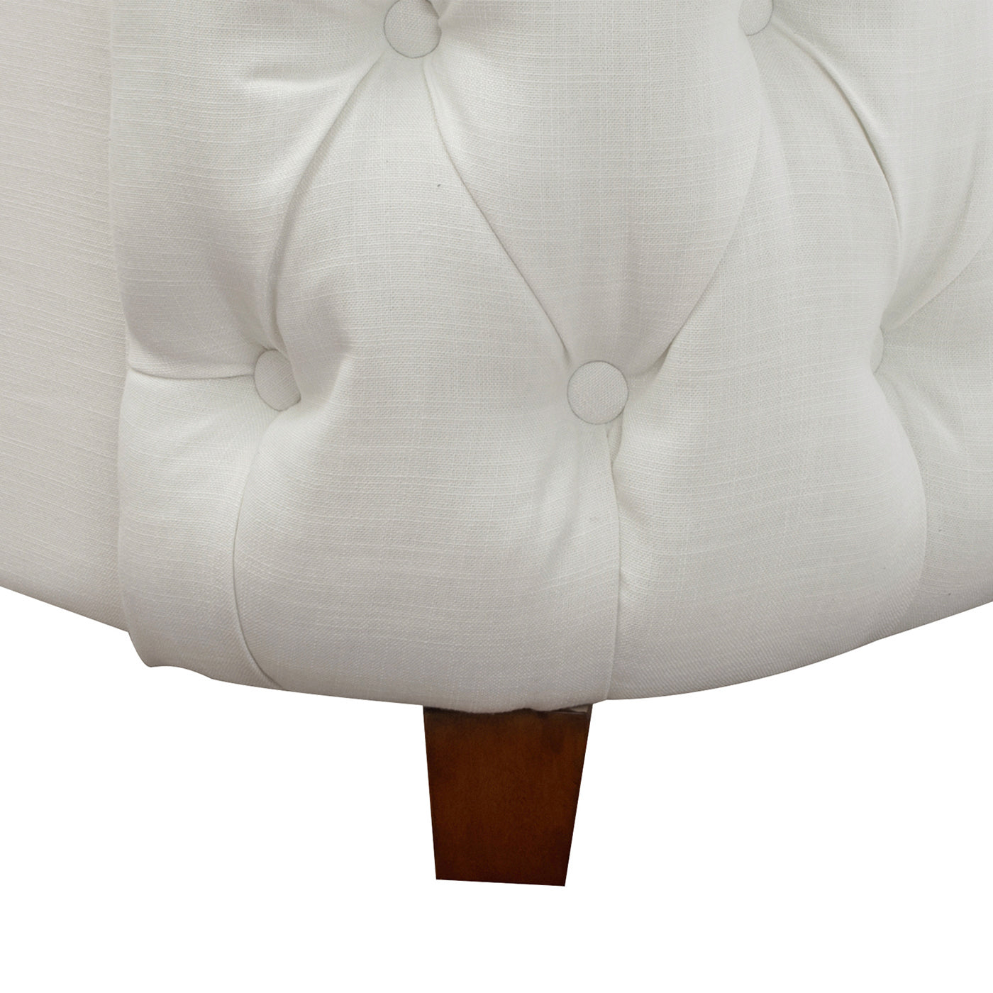 Closeup of a white linen upholstered ottoman with diamond tufting and wooden legs