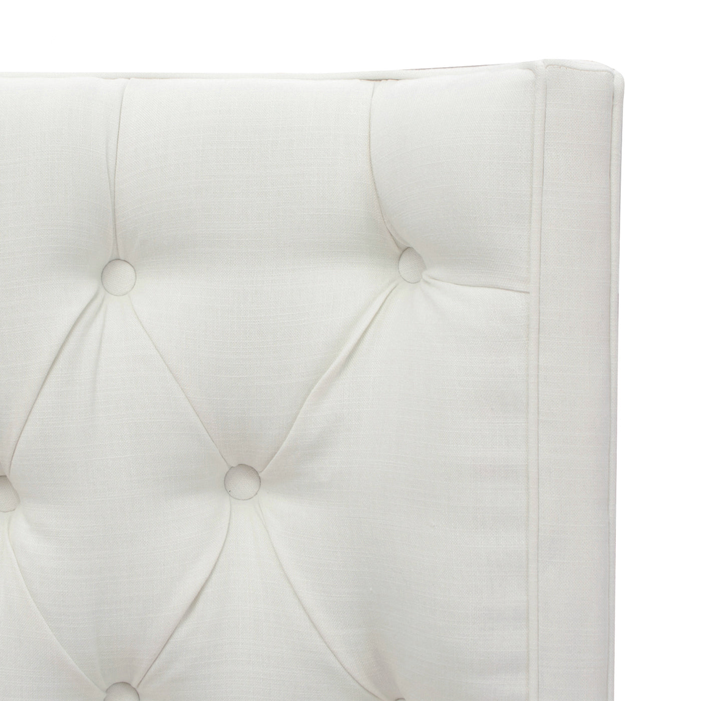 Close up of a white tufted linen headboard with diamond stitching detail