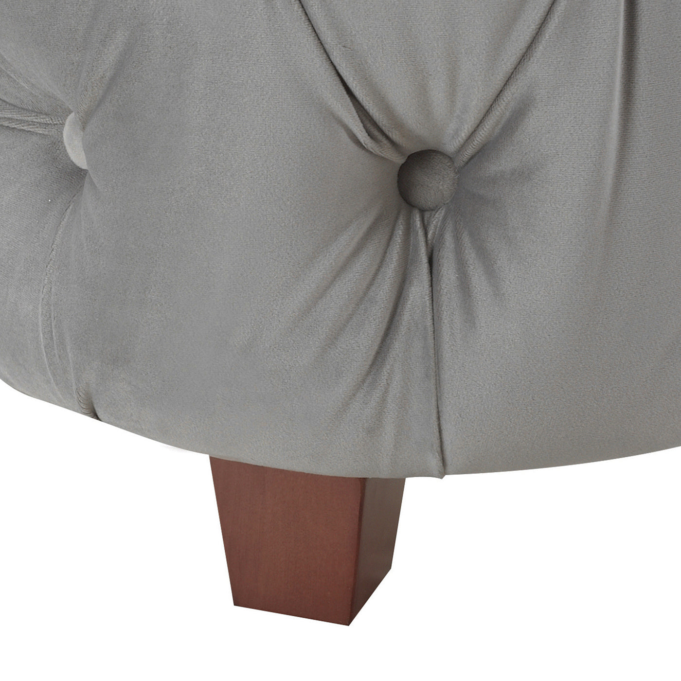 Closeup of a plush grey velvet tufted ottoman with a square wooden leg