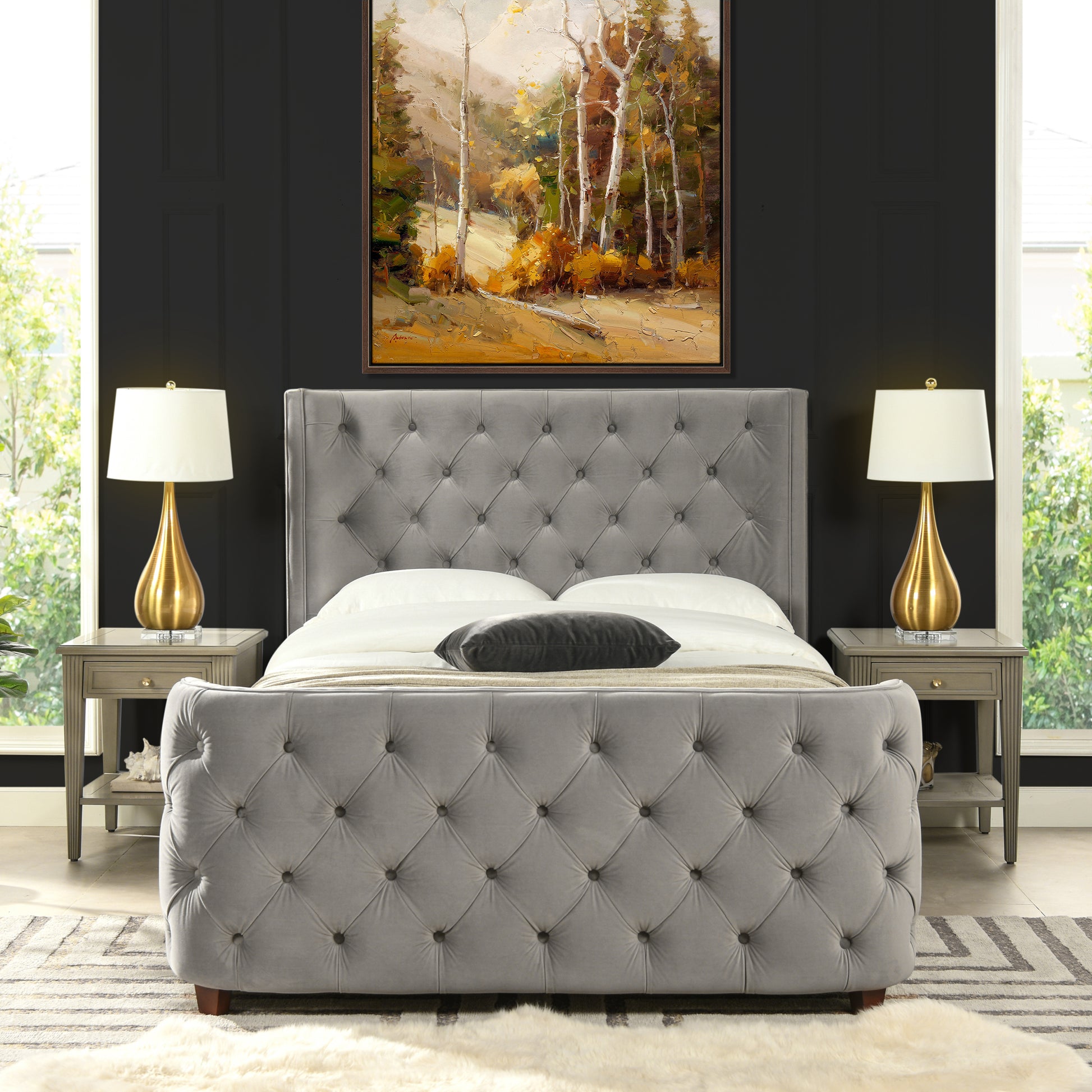 Tufted grey velvet sleigh bed with button details and ornate gold lamps on bedside tables