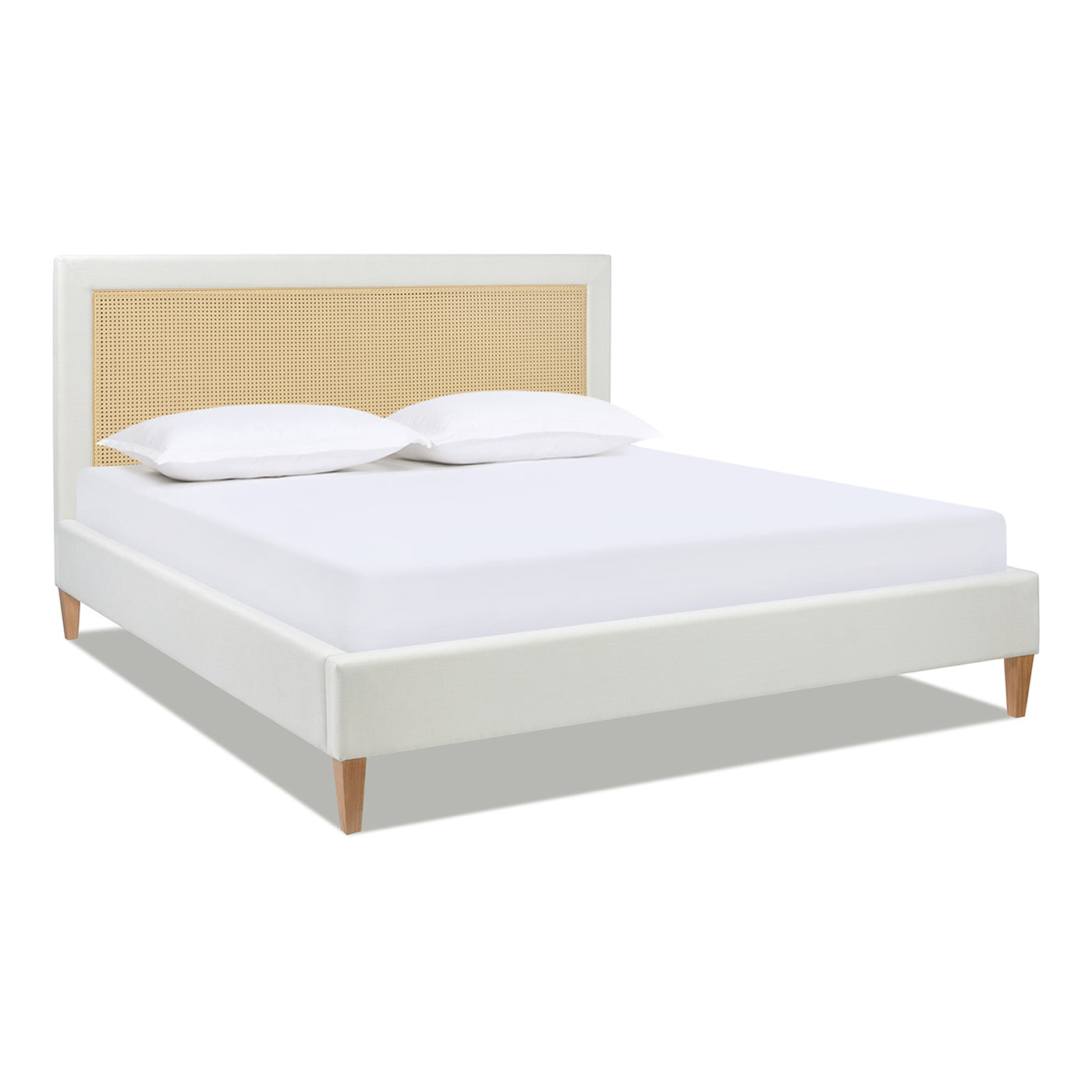 White upholstered platform bed with cane headboard and tapered wooden legs