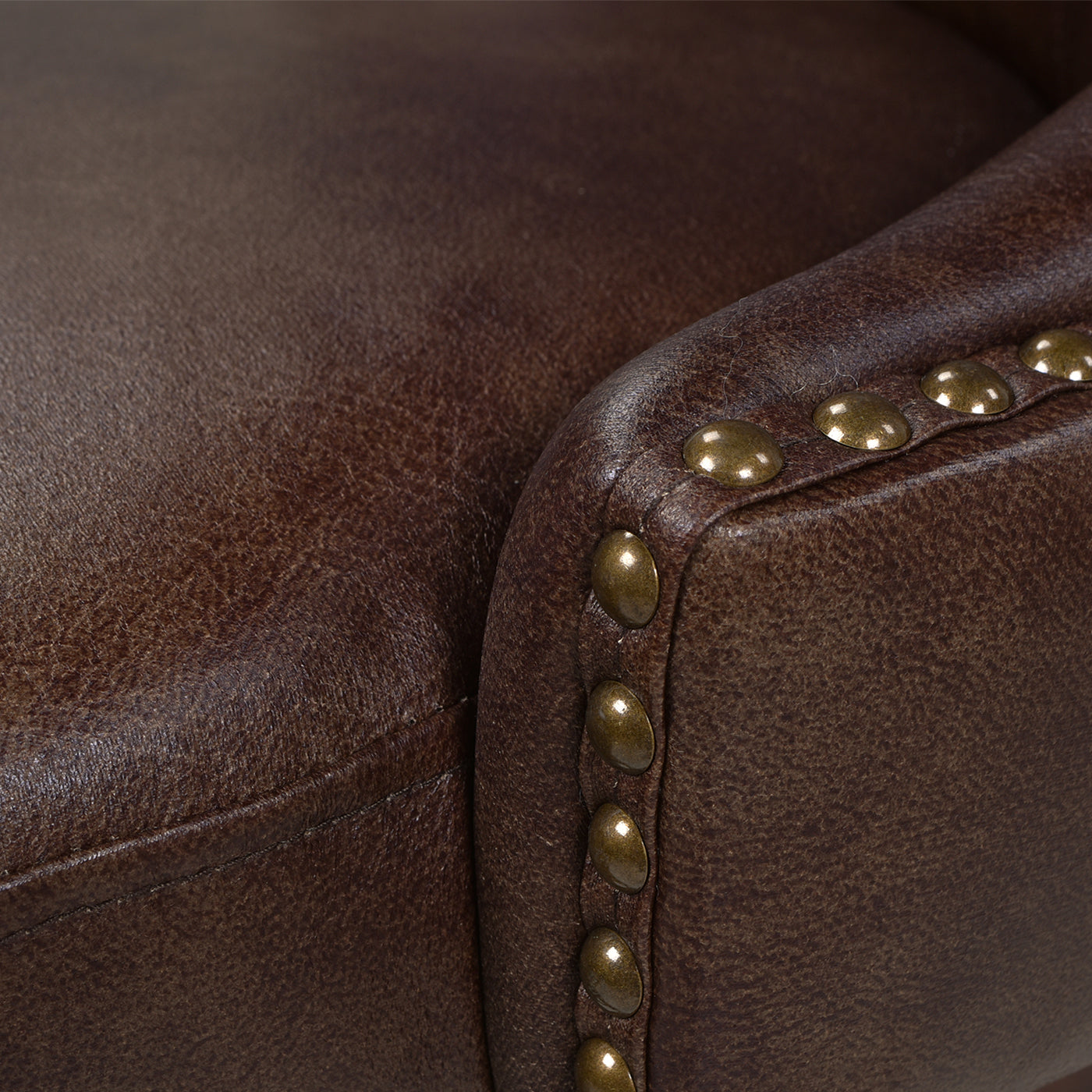 Closeup of a rustic brown leather armchair with brass stud accents