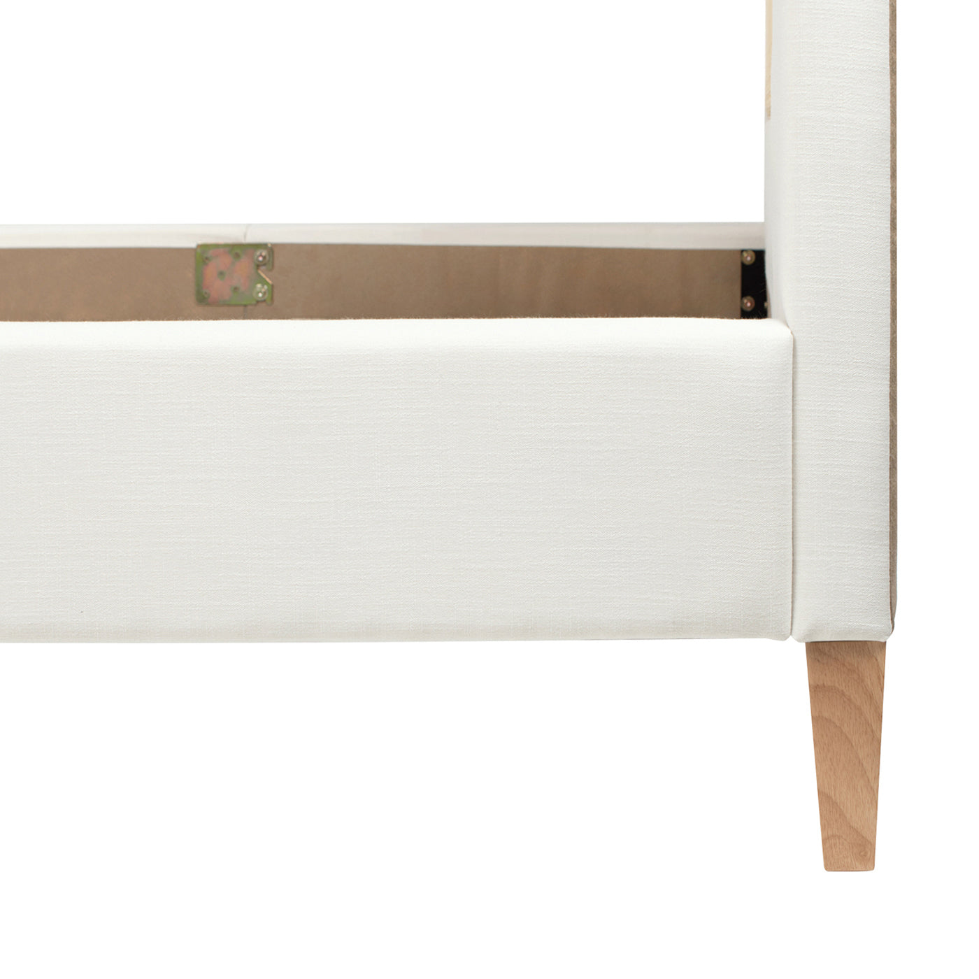 Closeup of a white upholstered bed frame with a wooden leg