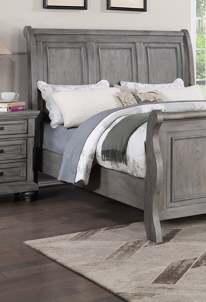Weathered gray wooden sleigh bed frame with upholstered headboard and decorative trim