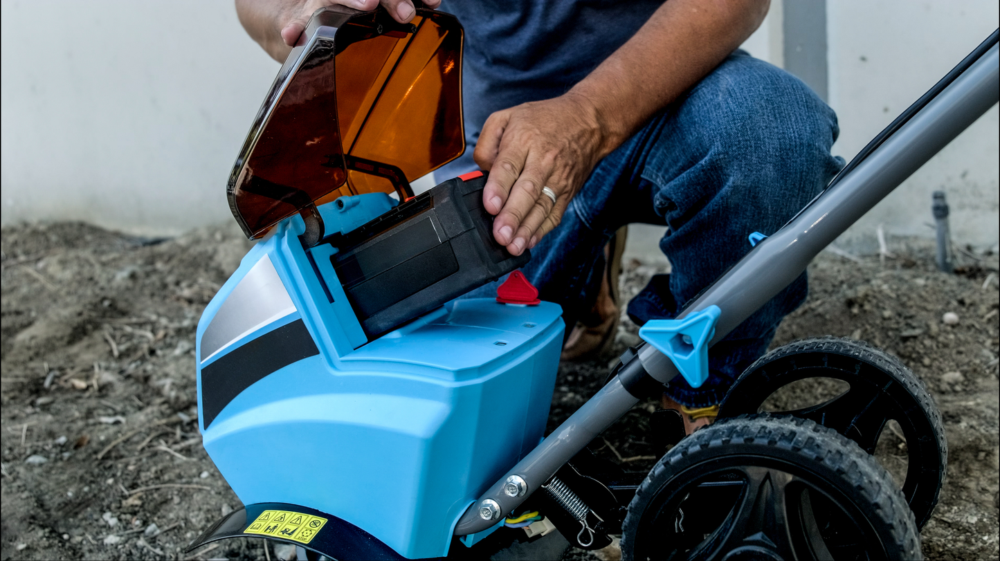 Person inserting battery into a blue electric tiller for yard work