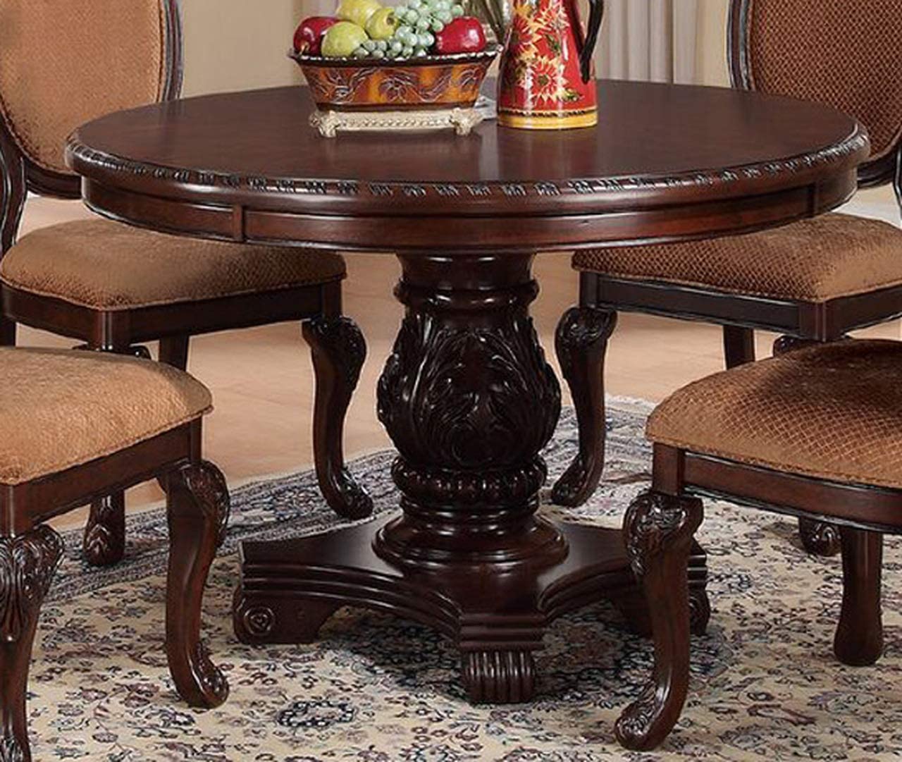 Ornate dark wood round dining table with carved pedestal and upholstered chairs