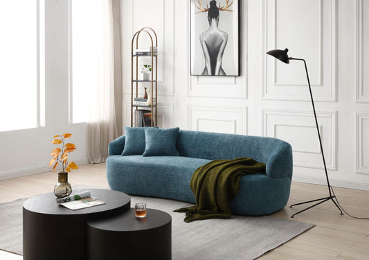 Curved teal boucle sofa with plush cushions and olive green throw blanket