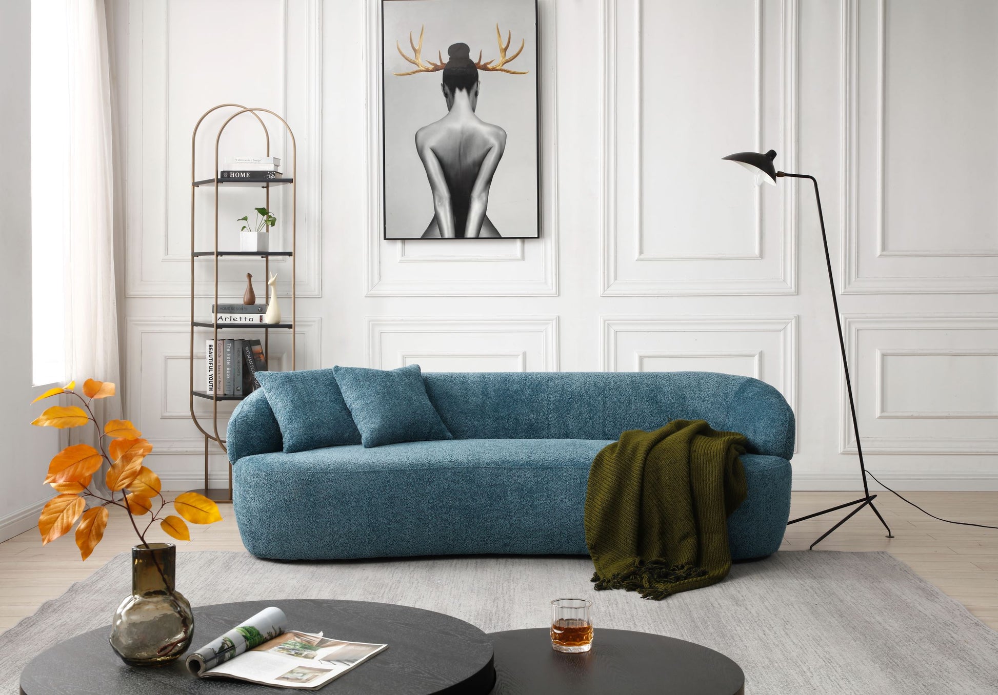 Teal boucle fabric sofa with two throw pillows and a green knit throw
