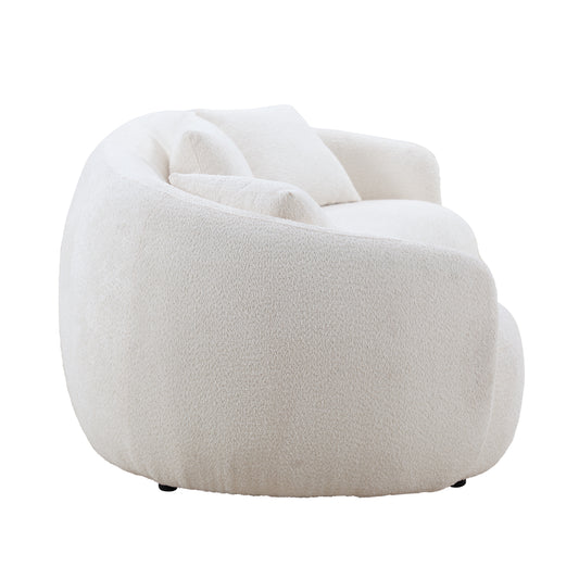 Plush cream boucle armchair with rounded silhouette and two accent pillows