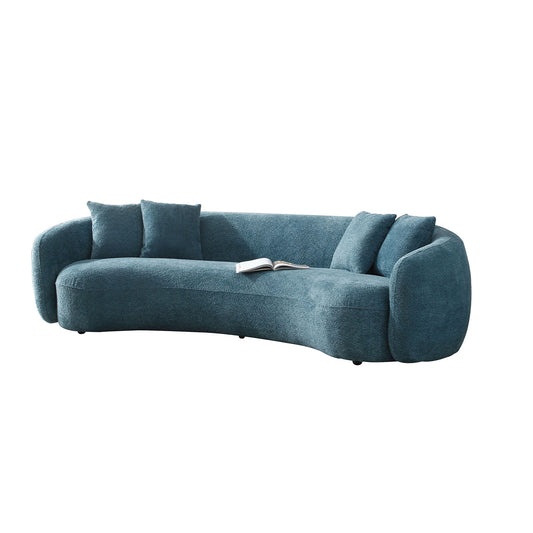 Teal boucl curved sofa with four plush throw pillows and an open book