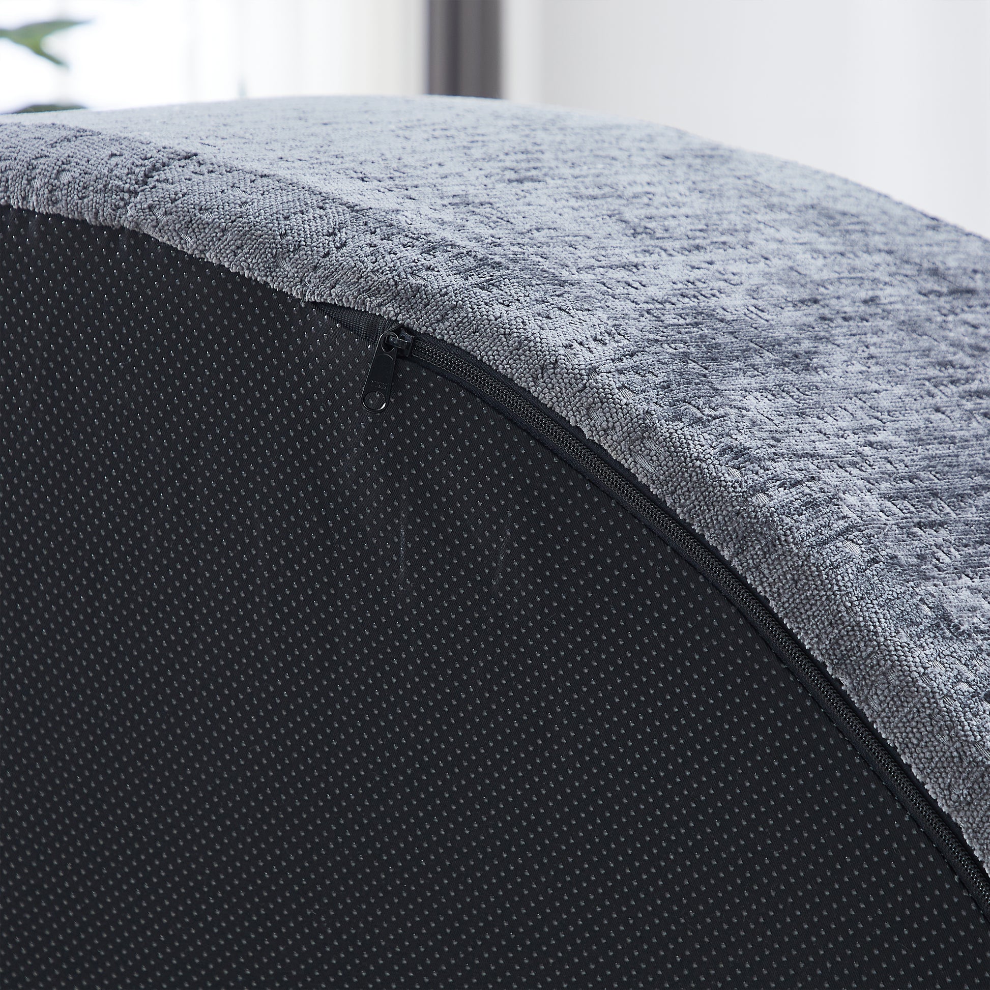 Closeup of textured grey fabric with a visible black zipper closure on a nonslip matting