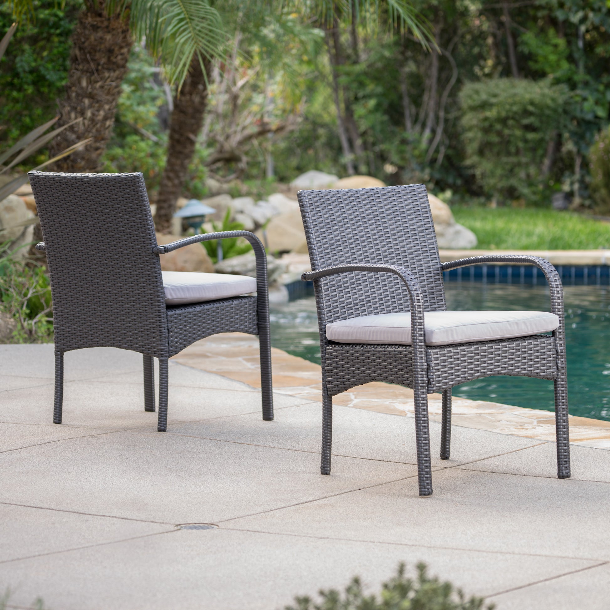 Dark grey wicker outdoor dining chair with light grey cushion poolside