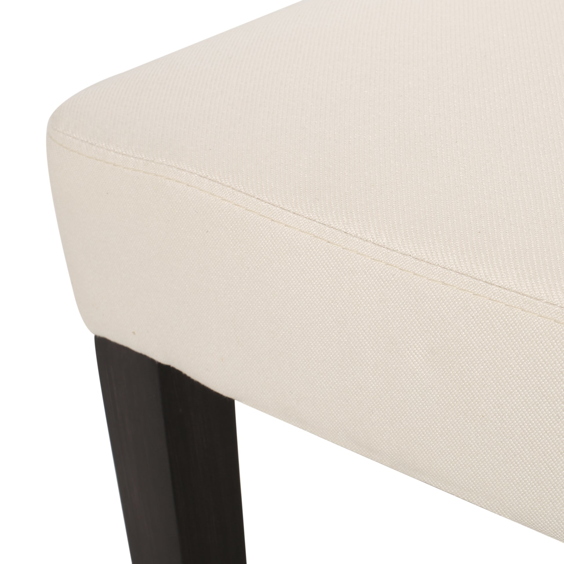 Closeup of cream linen upholstery on a dining chair with dark wood legs
