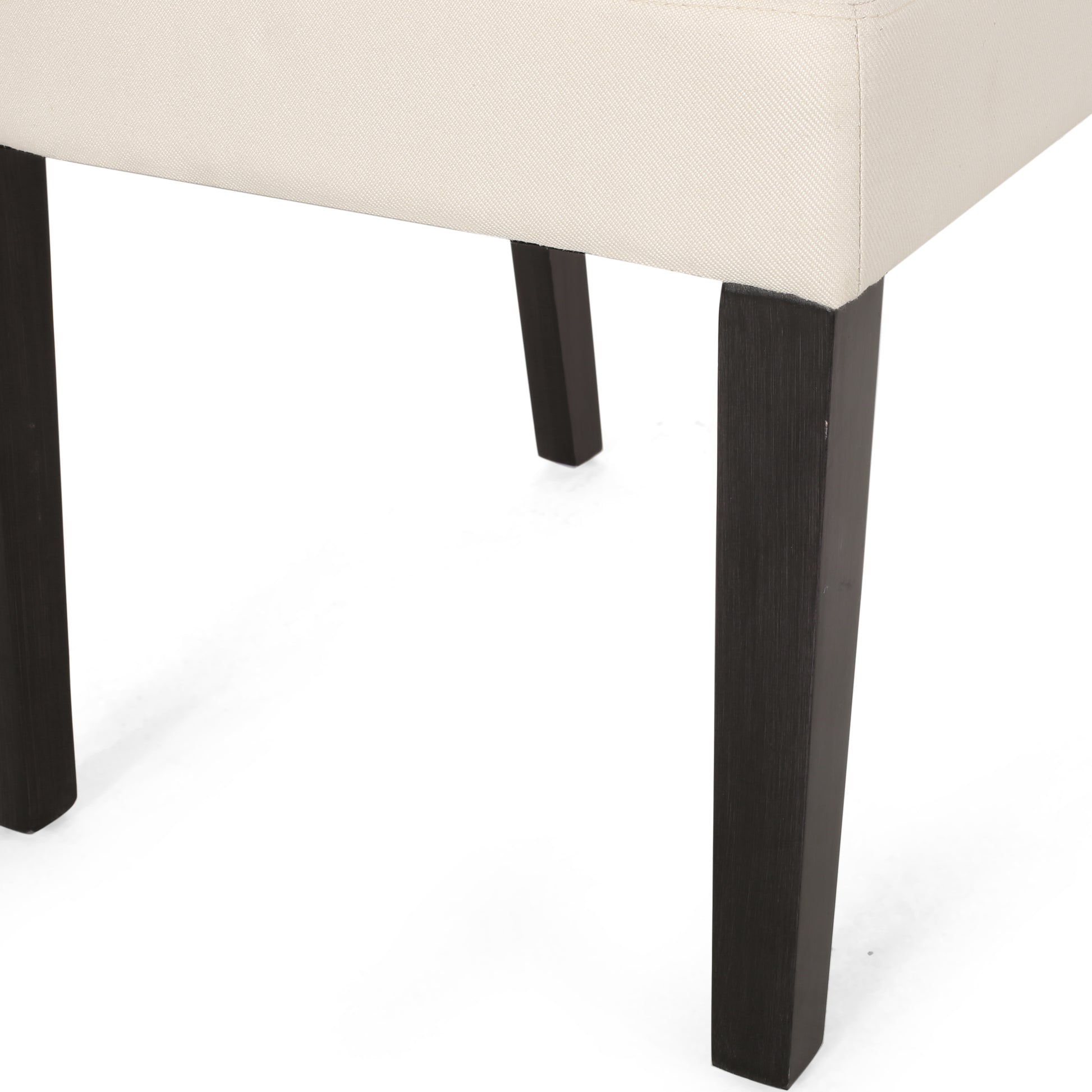 Close up of beige upholstered chair seat and dark wood legs on white background