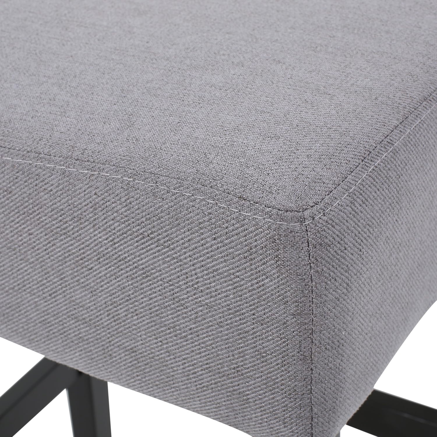 Closeup of grey fabric upholstery on a stool seat with visible stitching
