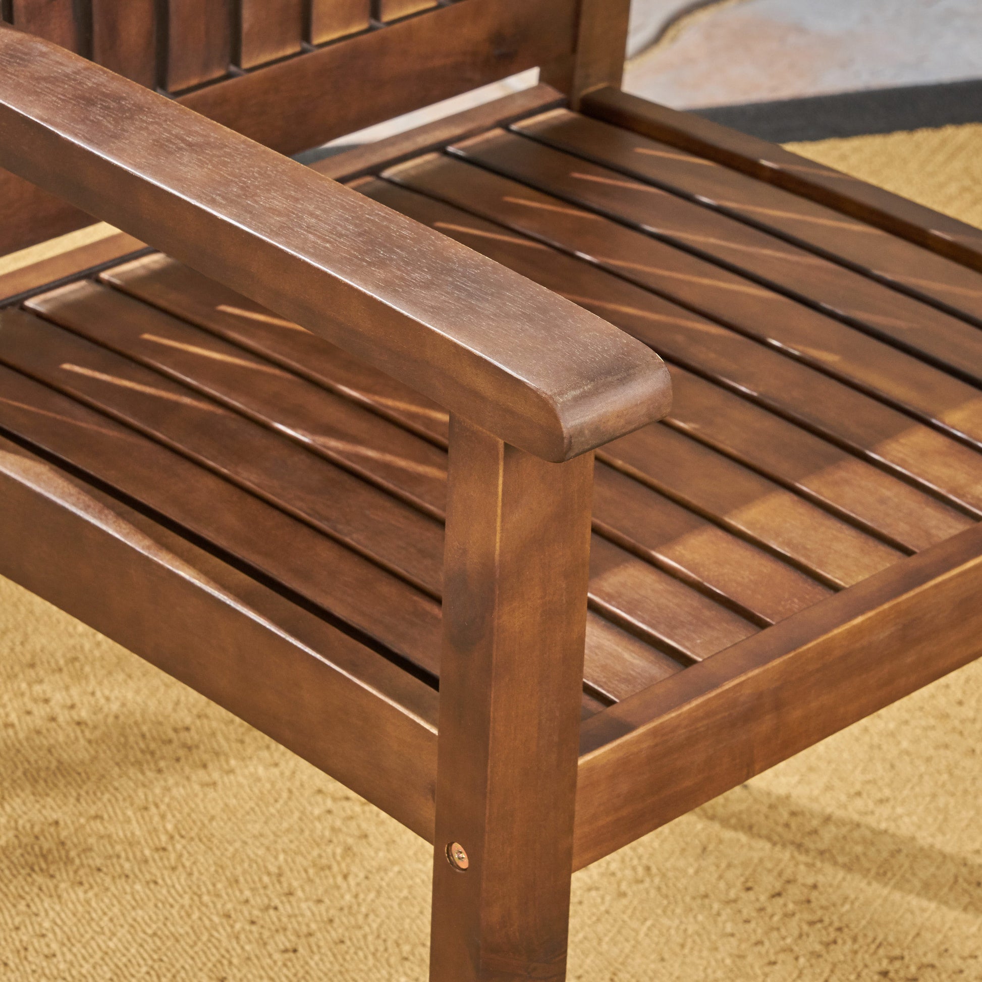 Closeup of a rich brown wooden Adirondack chair armrest showcasing its slatted design and outdoor patio setting