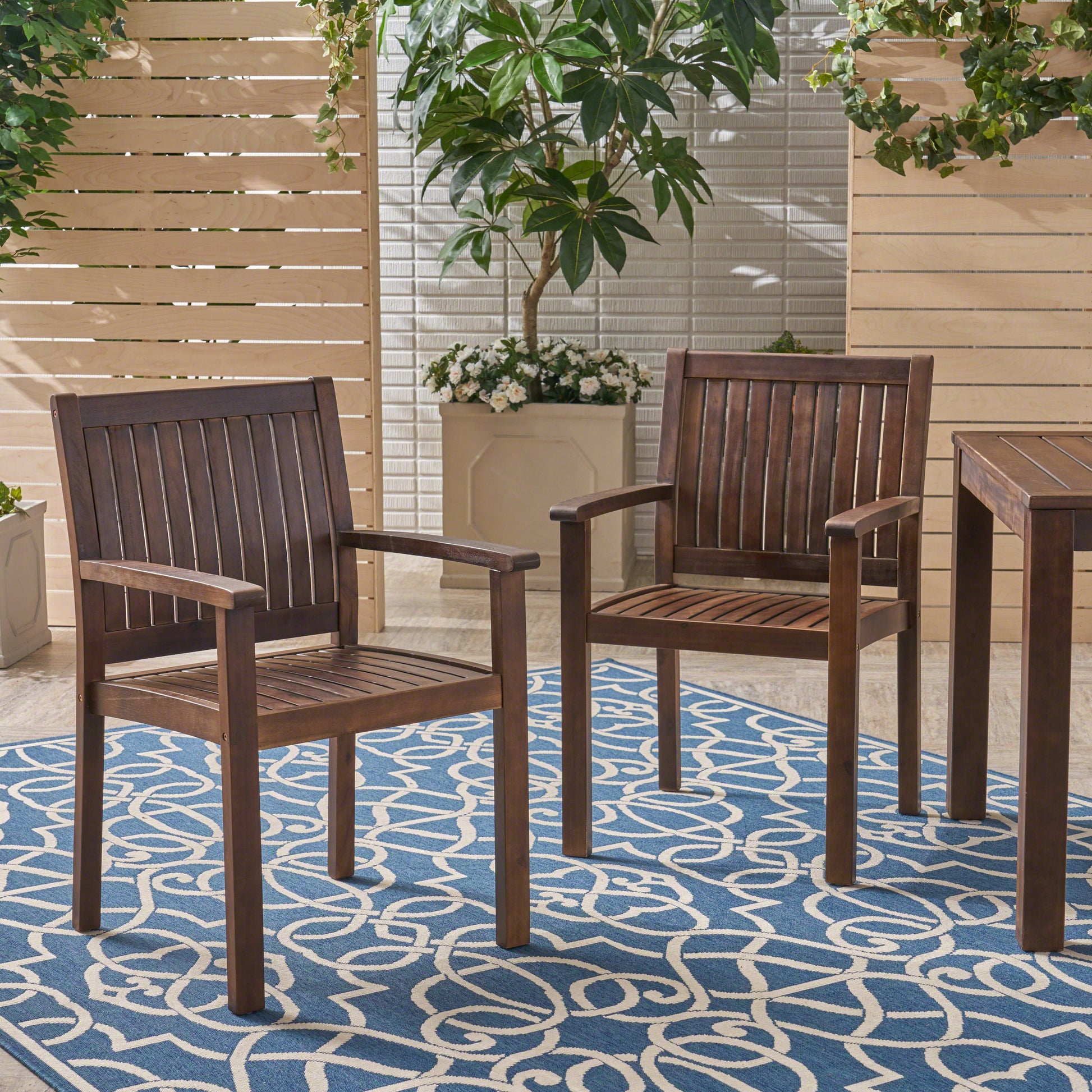 Two dark wood patio chairs with slatted backs and seats on a blue and white geometric rug