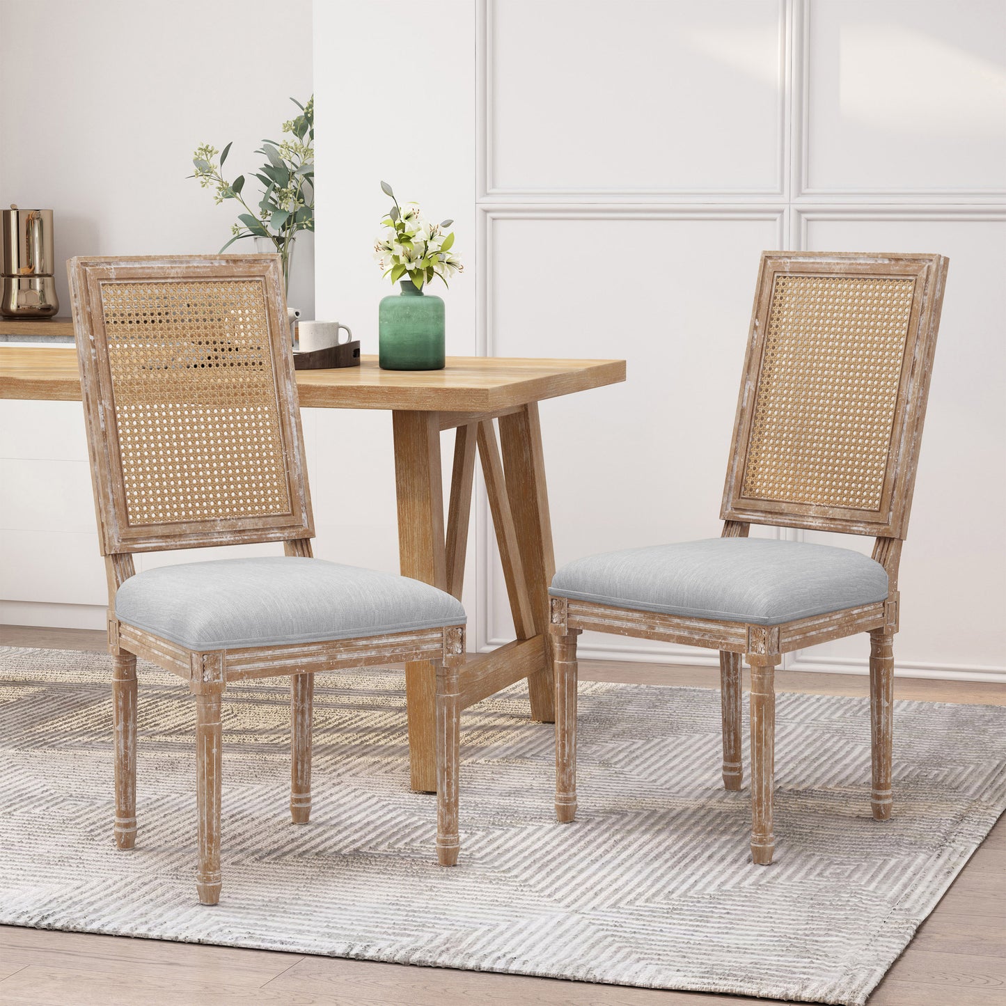 Two rustic distressed wood dining chairs with cane backs and grey upholstered seats