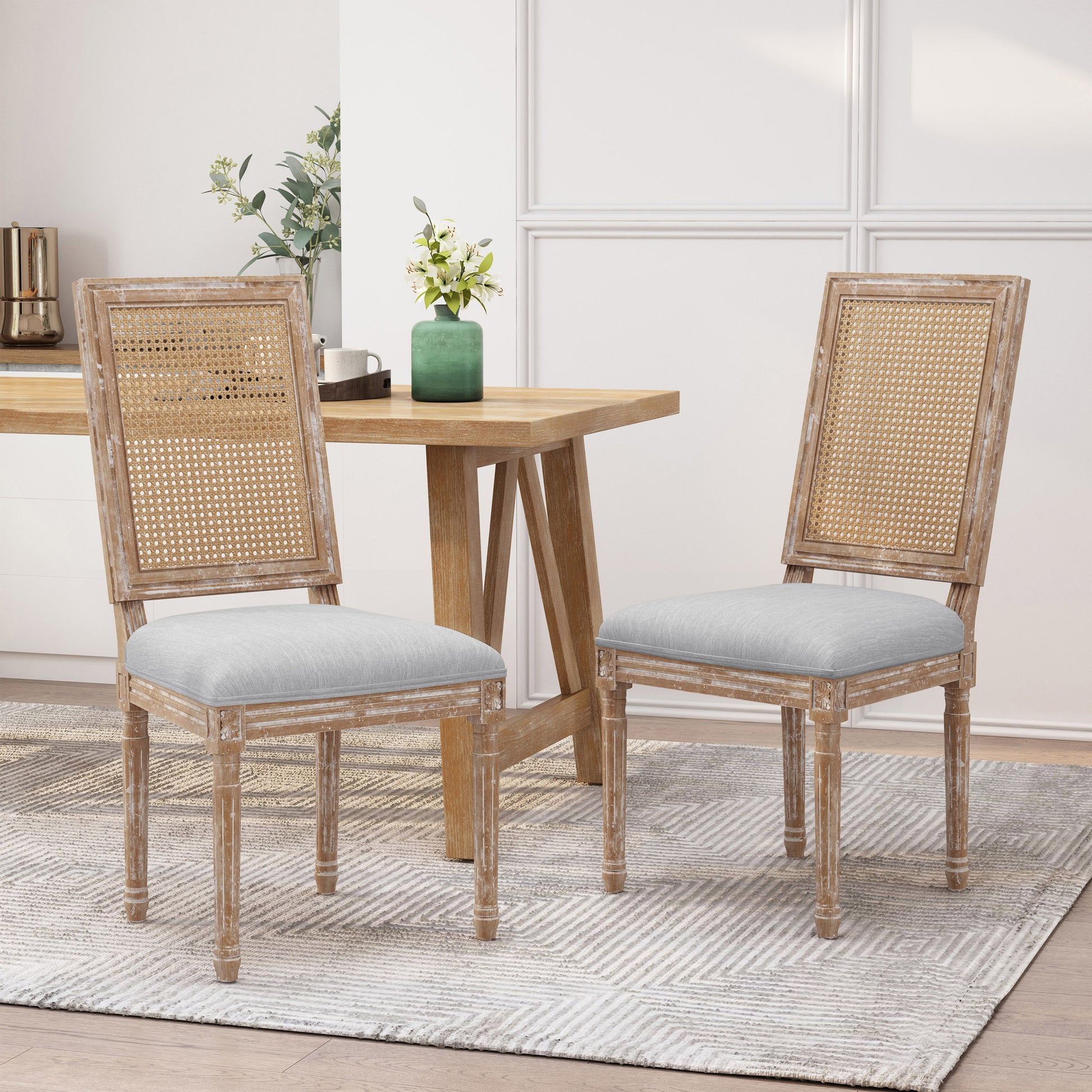 Two rustic distressed wood dining chairs with cane backs and grey upholstered seats