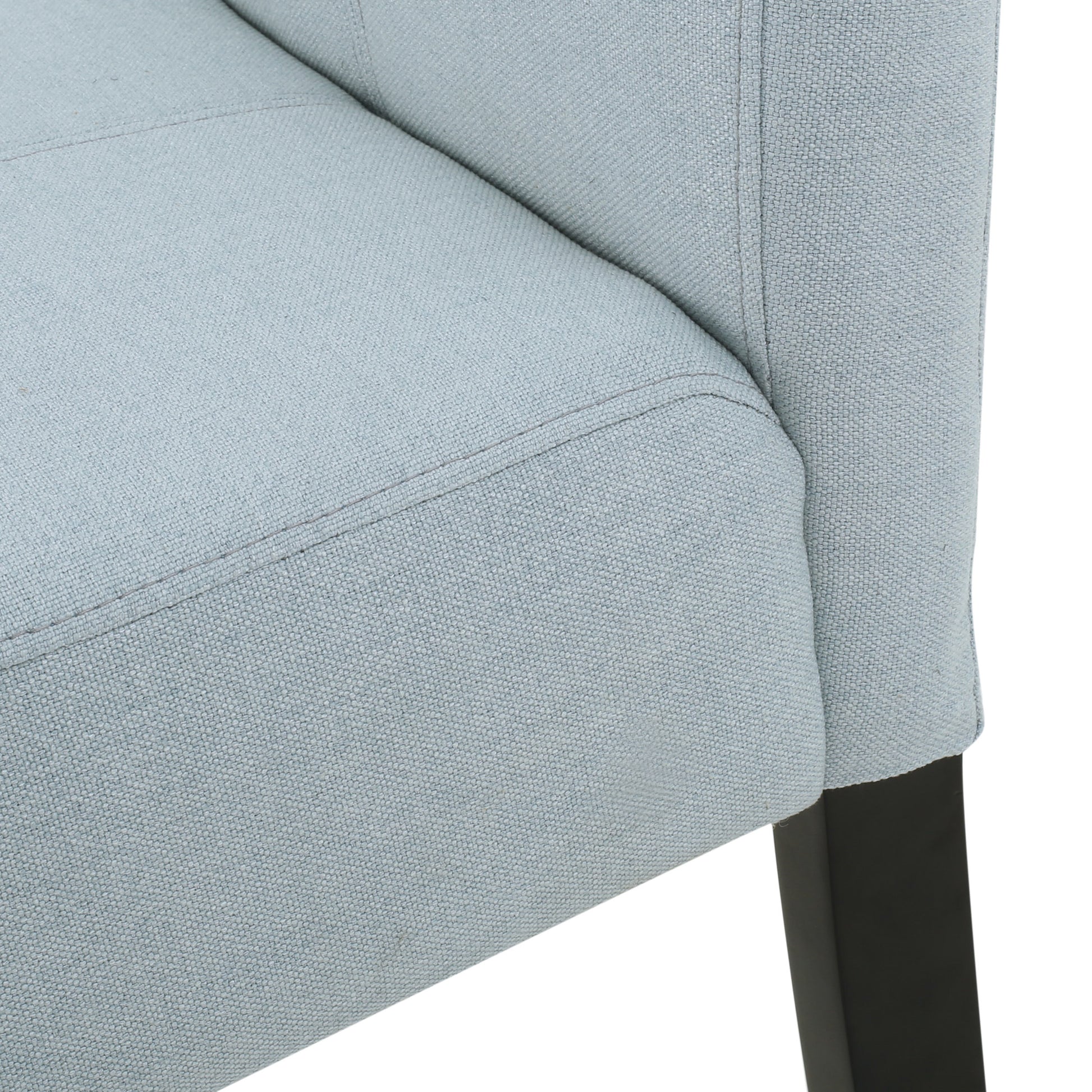 Closeup of a light blue upholstered chair showing textured fabric and subtle stitching detail