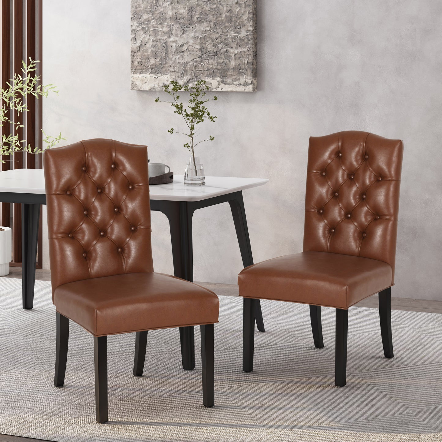 Two brown faux leather tufted dining chairs with dark wood legs