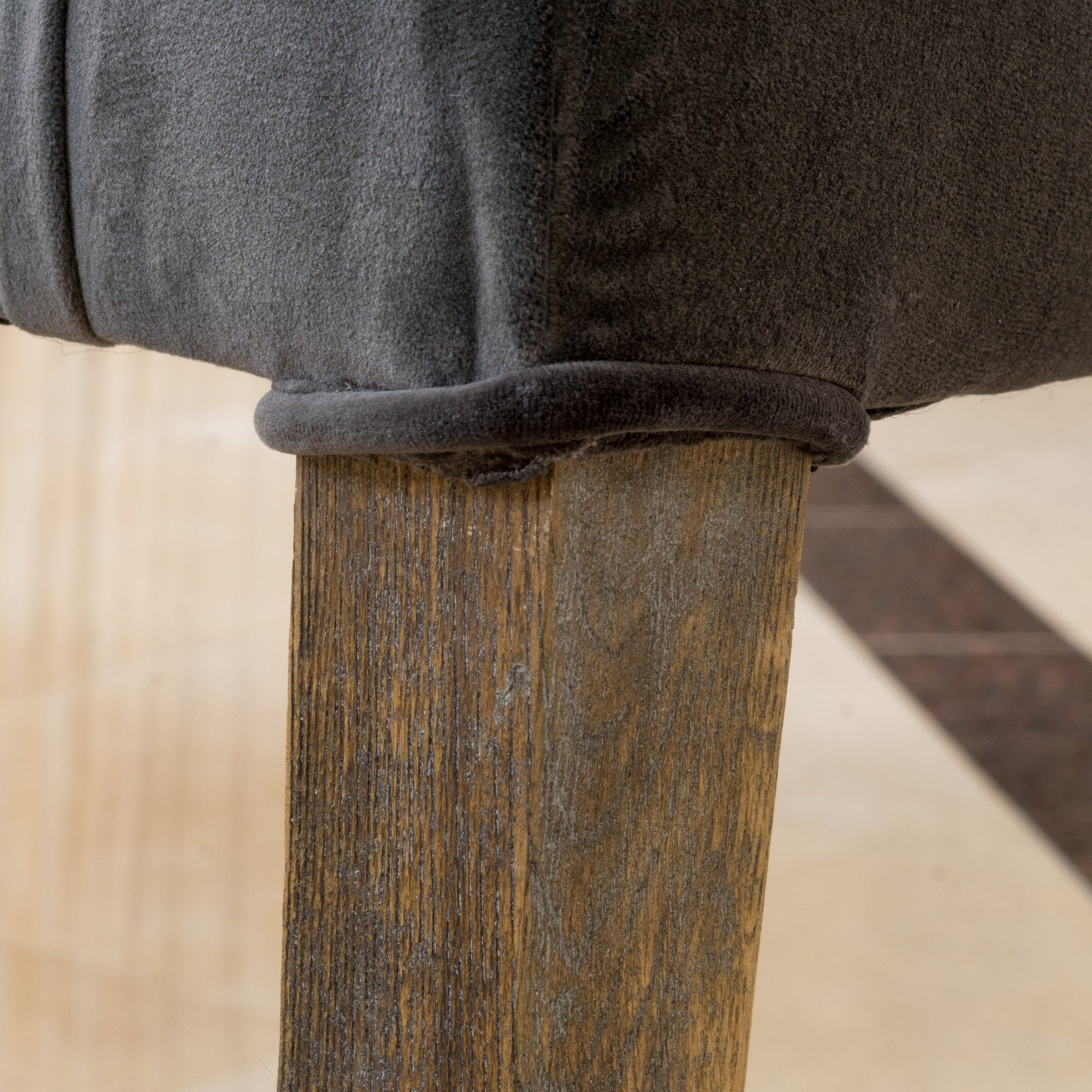 Dark grey textured fabric upholstery on a rustic wooden table leg
