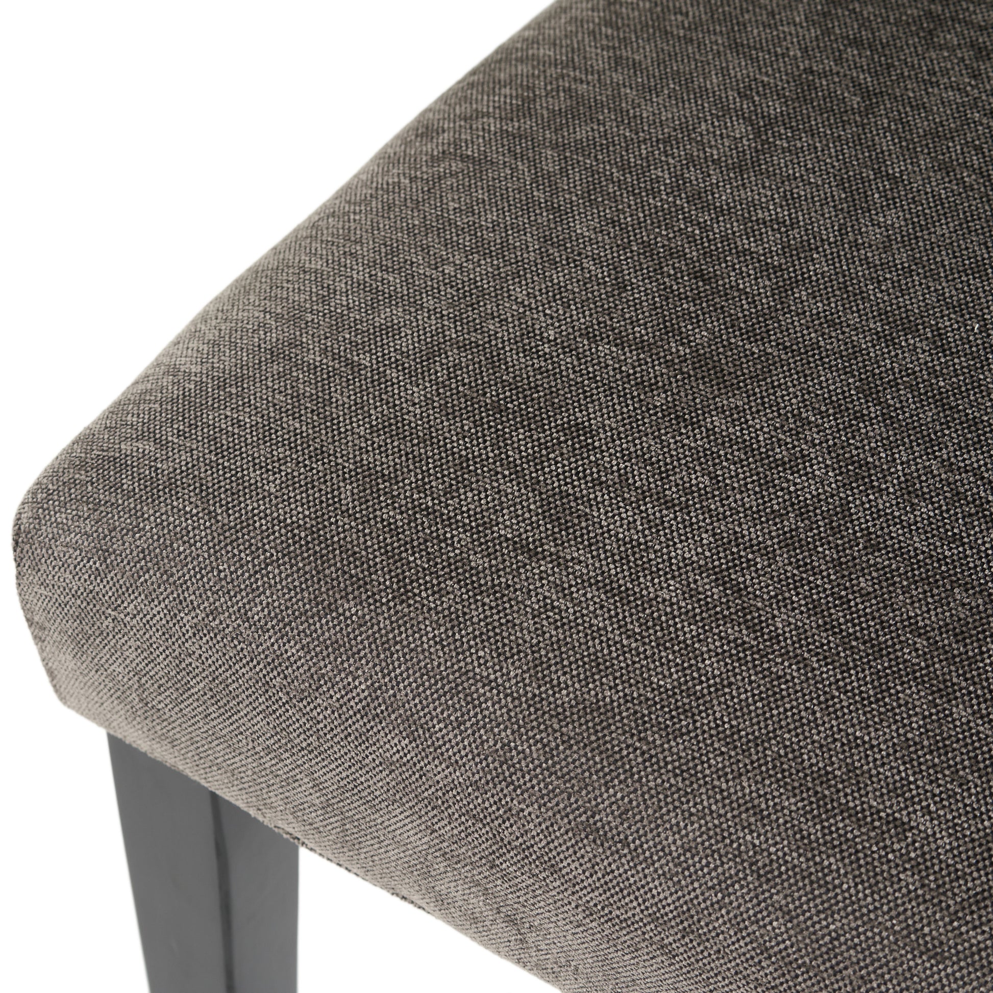 Closeup of dark gray textured fabric seat cushion on a dark wooden chair leg