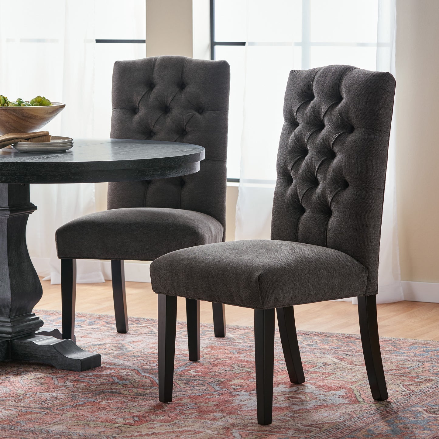 Dark gray upholstered dining chair with tufted backrest and dark wood legs