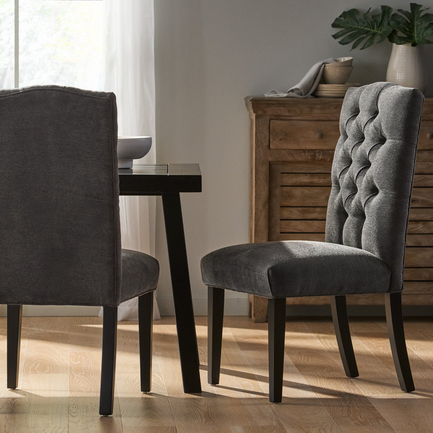 Dark gray fabric dining chair with tufted back and wooden legs