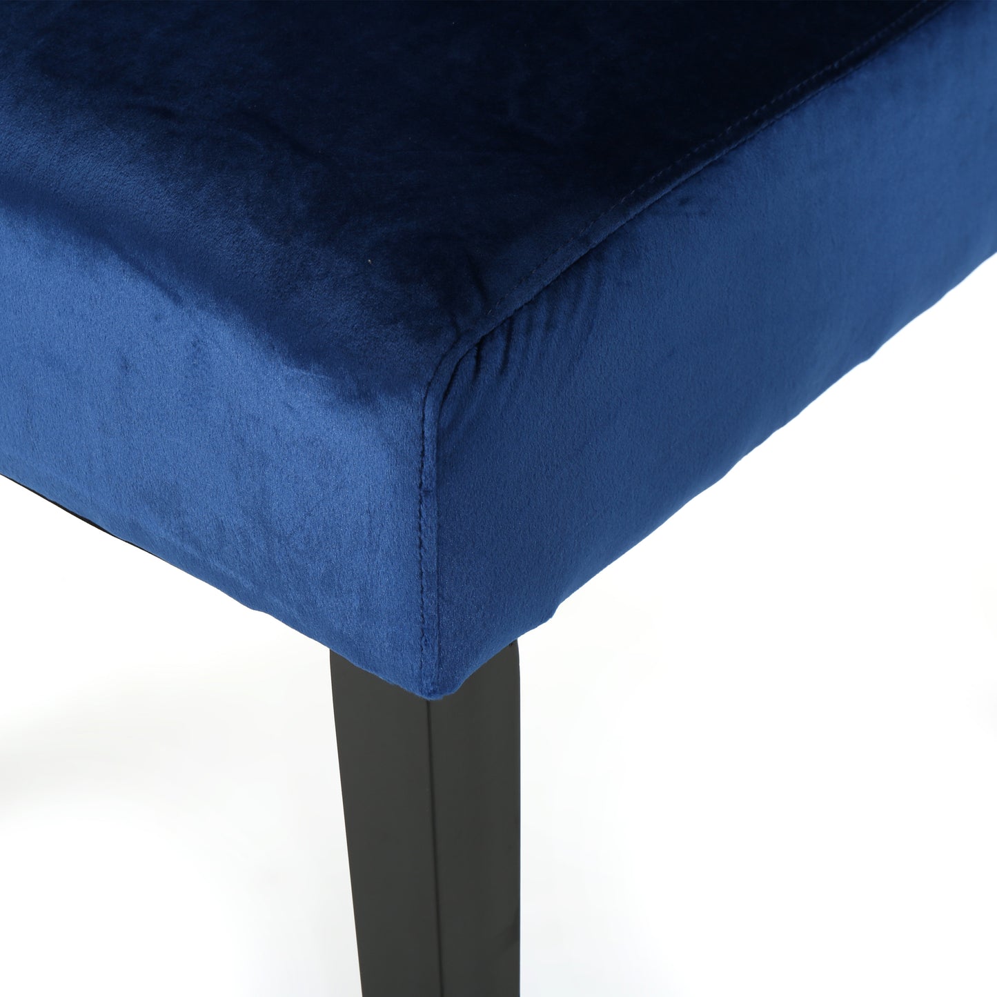 Closeup of a navy blue velvet upholstered seat corner with black metal legs