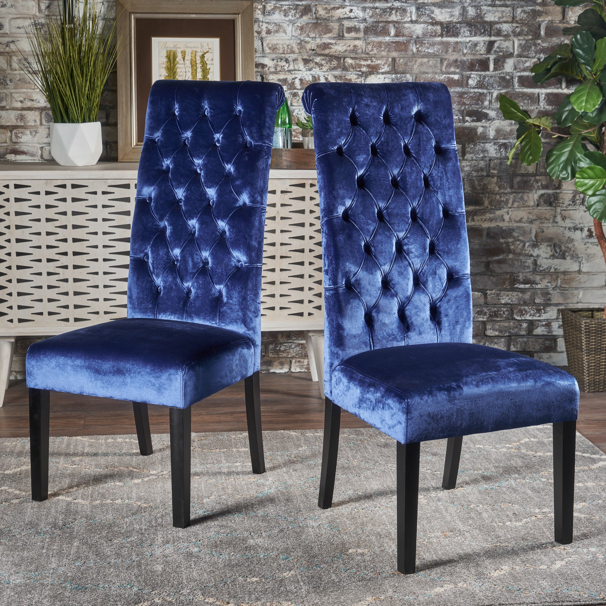 Two plush navy velvet dining chairs with diamond tufting and dark wooden legs