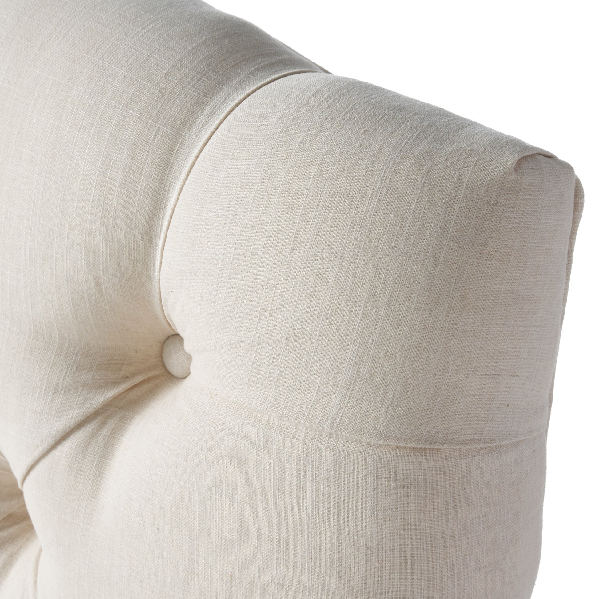 Closeup of cream tufted linen upholstered armchair detail with button accent