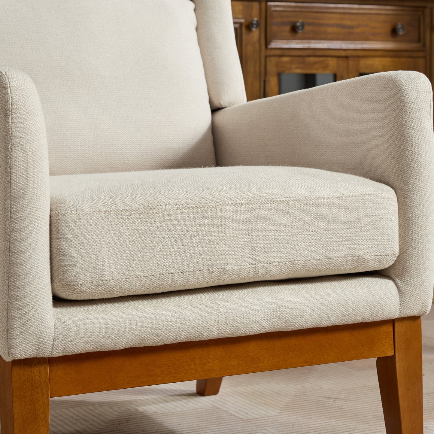 Closeup of a modern beige fabric armchair with natural wood legs