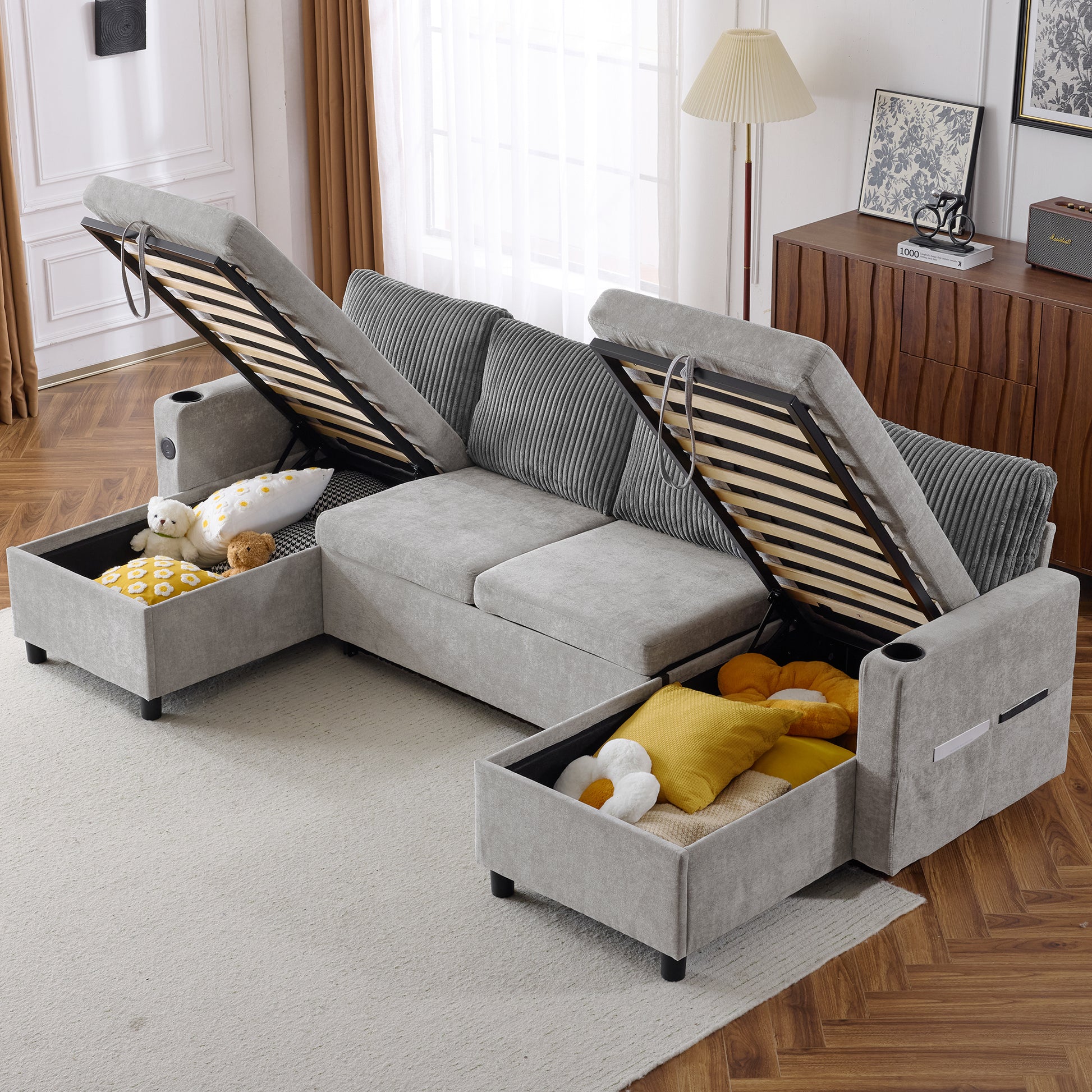 Grey sectional sofa with open storage compartments revealing bedding and pillows for a comfortable living room