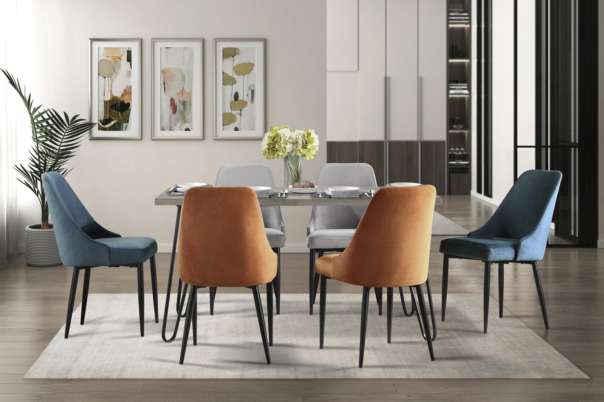 Contemporary dining set with four velvet chairs two orange and two teal surrounding a grey table