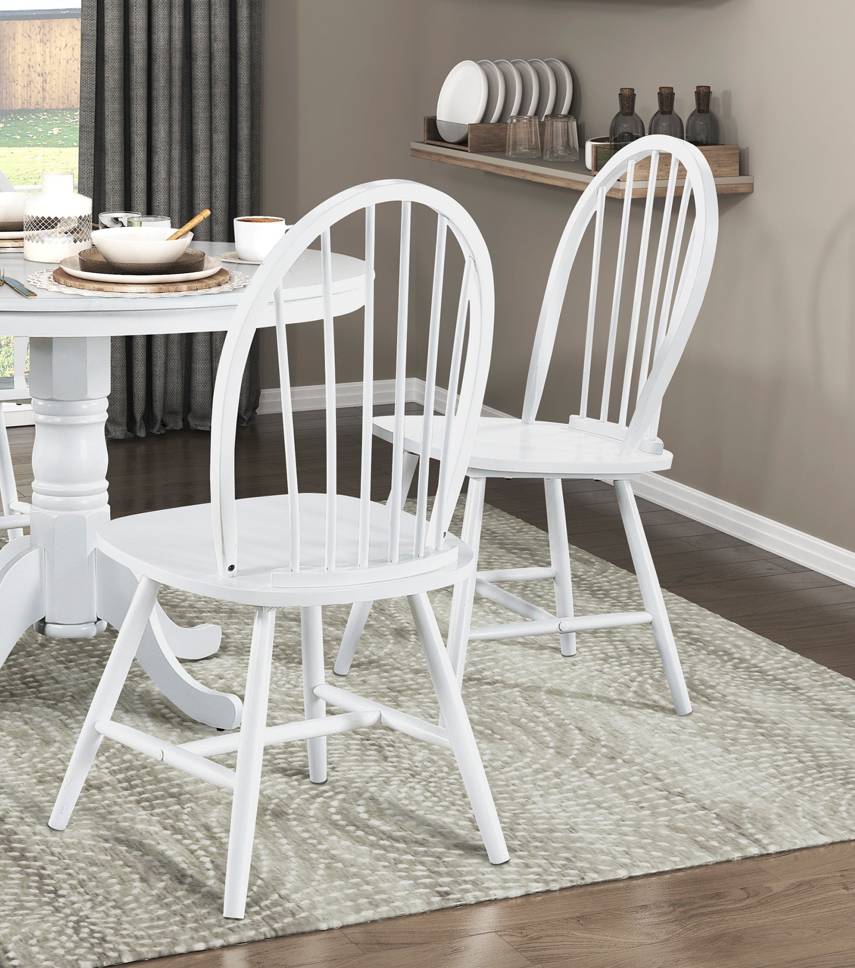 Two white wooden dining chairs with spindle backs at a round table